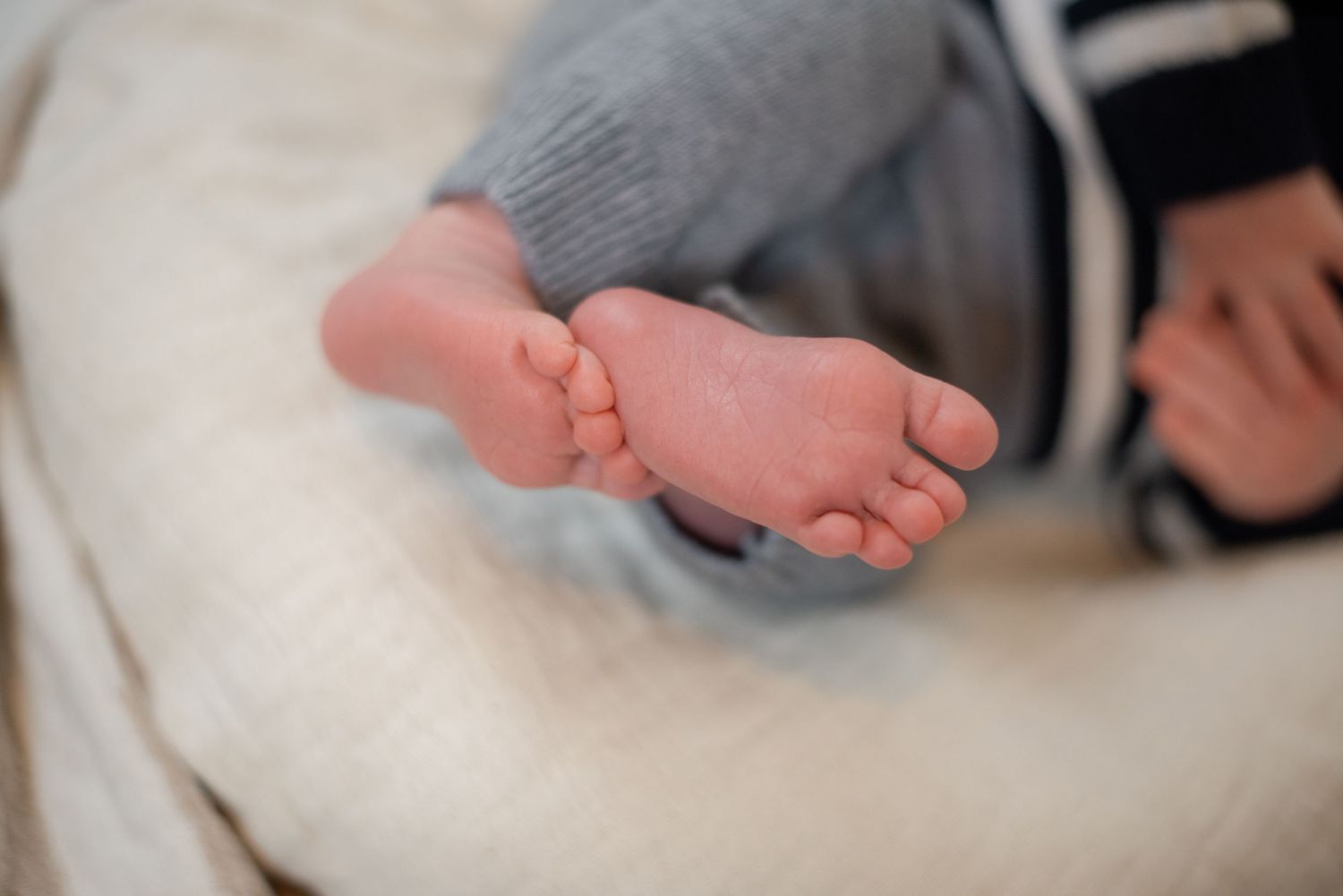 Close-up of tiny baby feet against white fabric background.