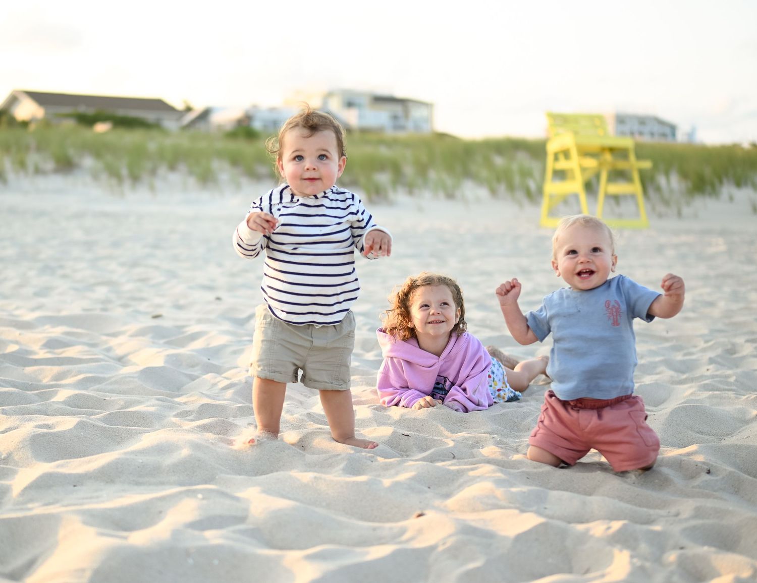 Multiple children playing together on a sandy beach during sunset.
