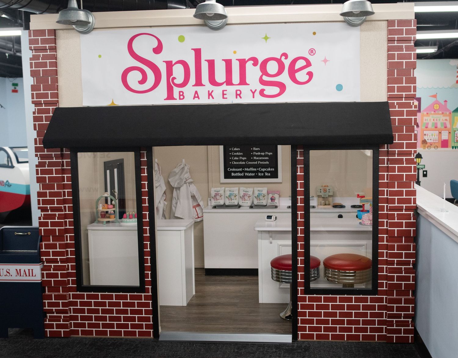 Brick-styled storefront with 'Splurge Bakery' signage in pink lettering.