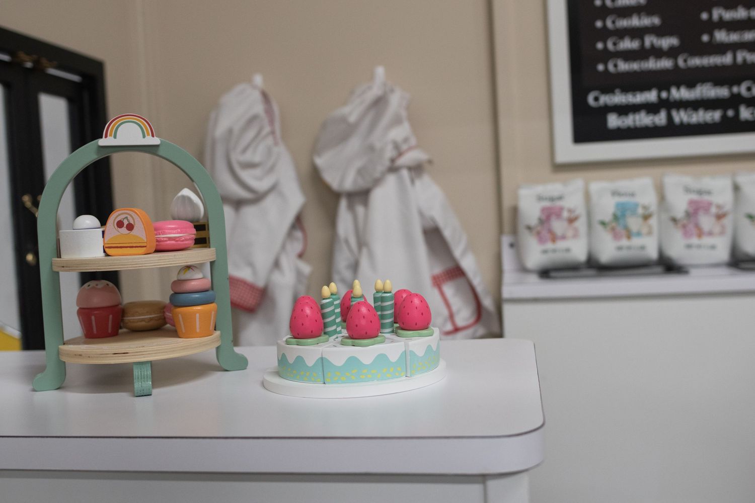 Display case showing assorted baked goods and treats with small decorative items on top.
