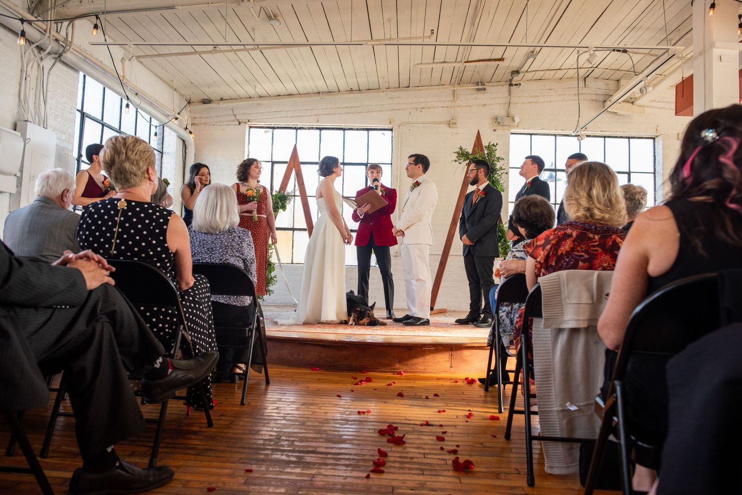 Wedding guests gather in an industrial venue to watch a ceremony.