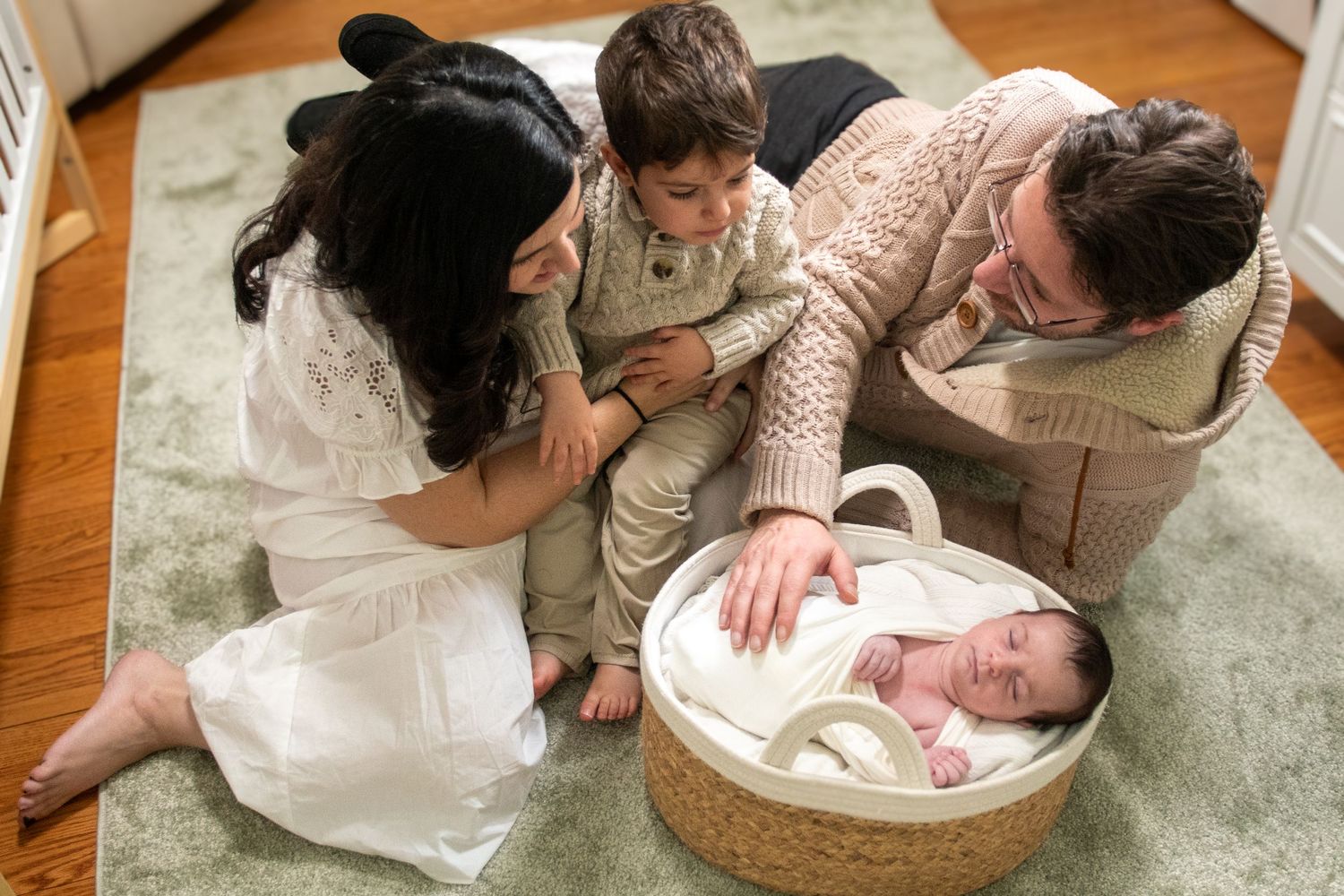 Indoor photo session showing baby being carefully positioned on floor.