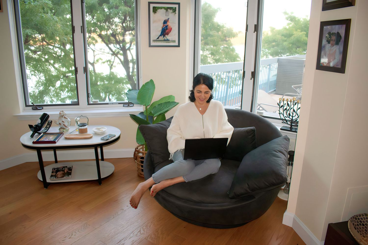 Modern interior with large windows, comfortable grey armchair and wall art.