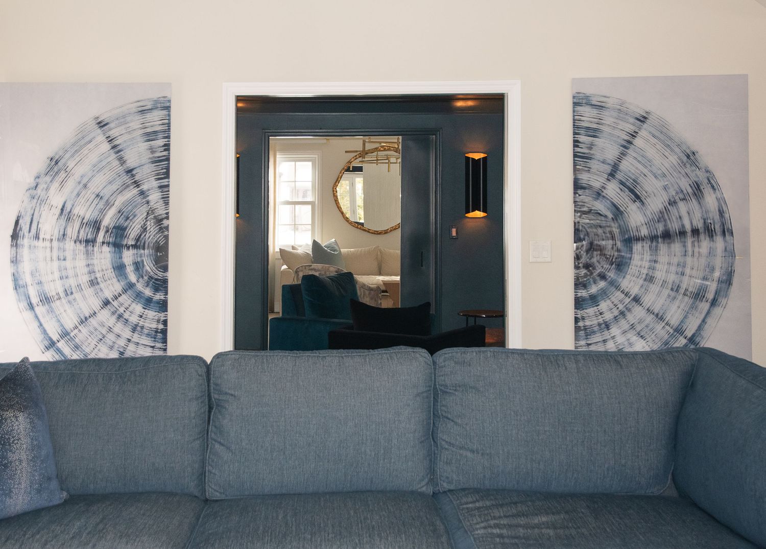 Modern gray sectional sofa with blue circular wall art patterns in background.