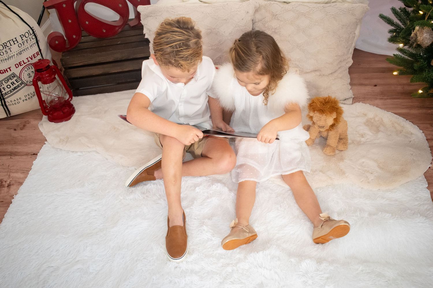 Children's feet in white clothing sit together on white fabric showing family connection.