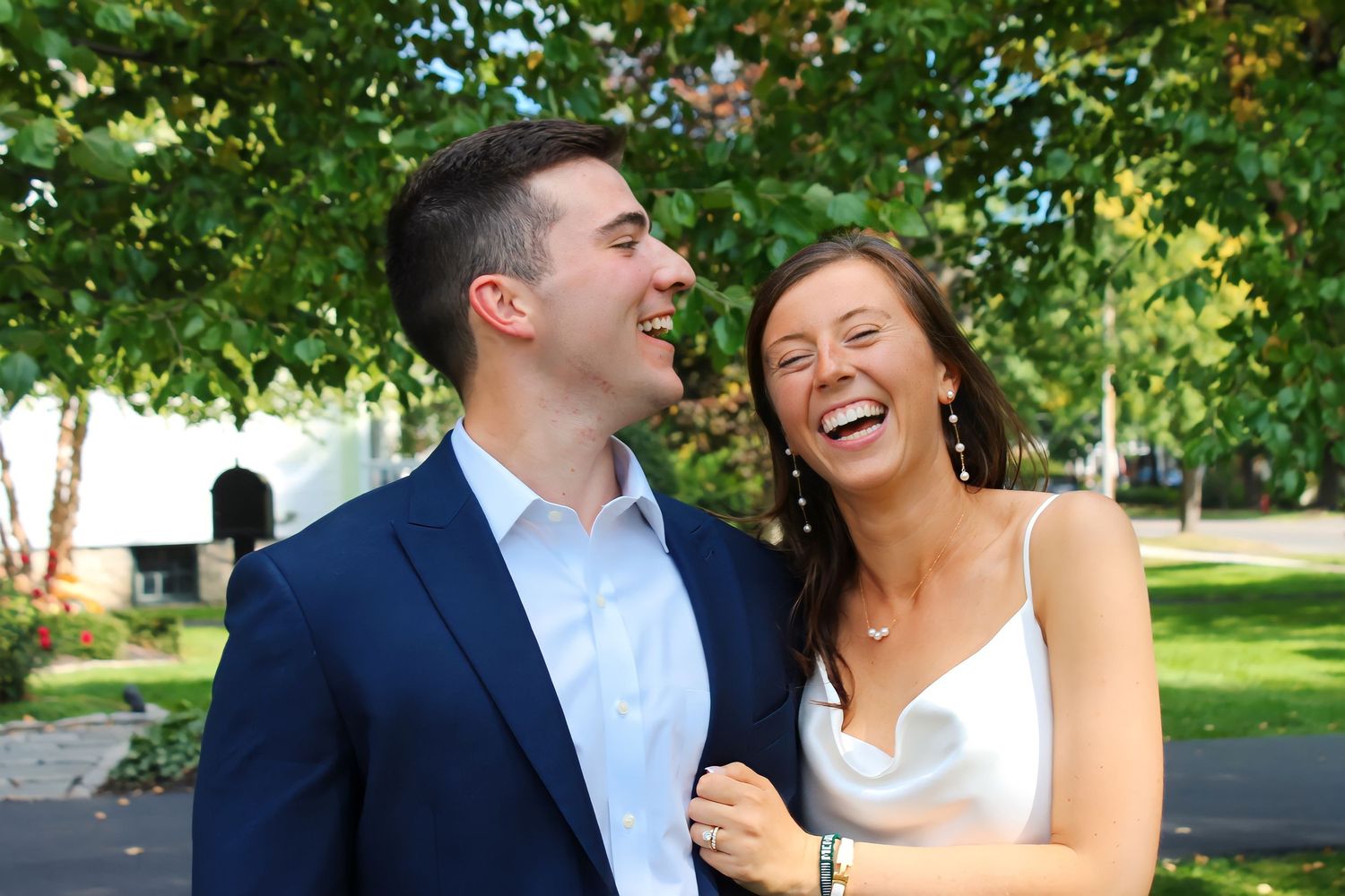 A couple laughs together outdoors on a sunny summer day.