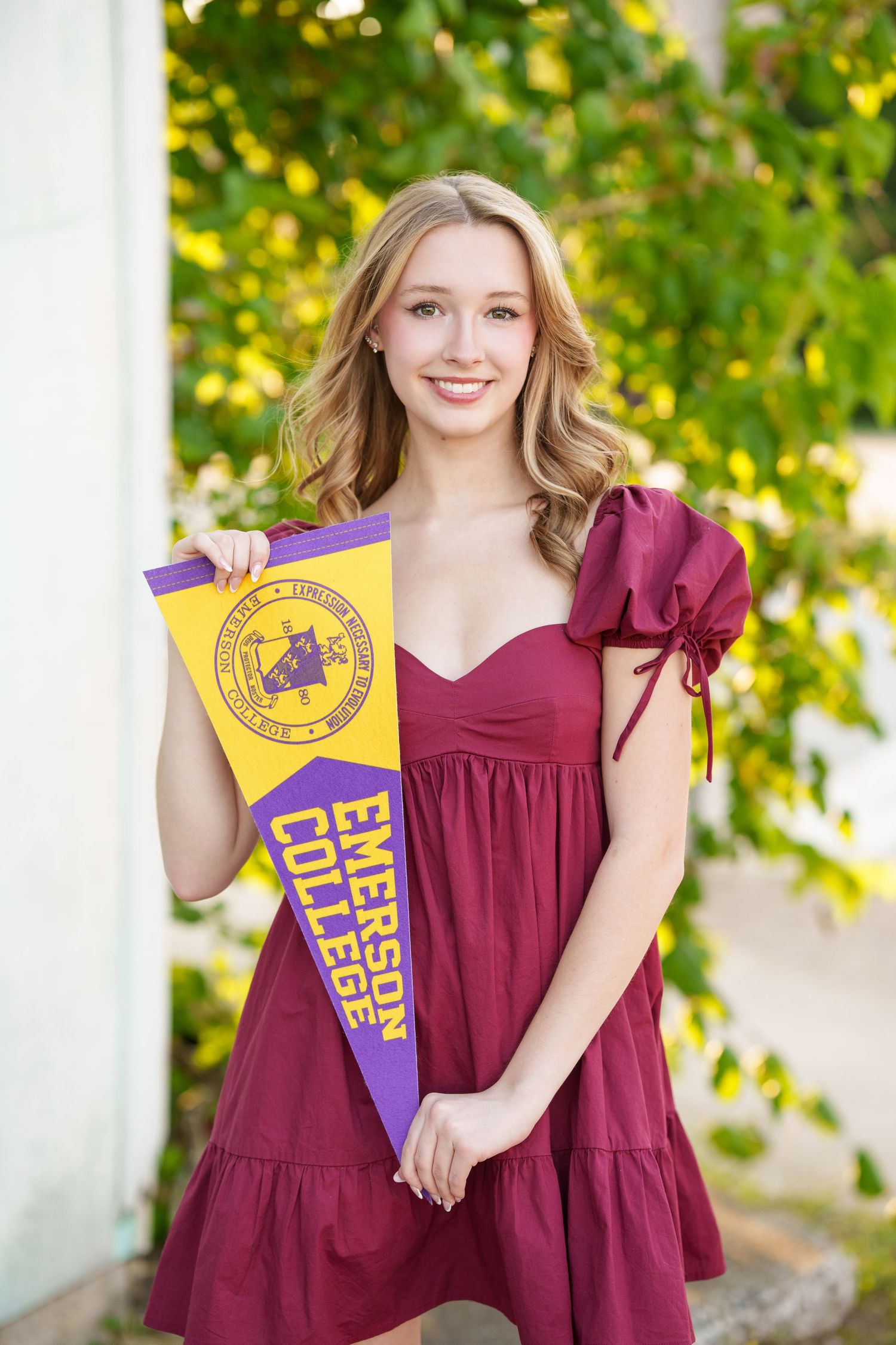 Posing with college pennant  for senior photos.  The woodlands senior photographer sessions for showing college gear.