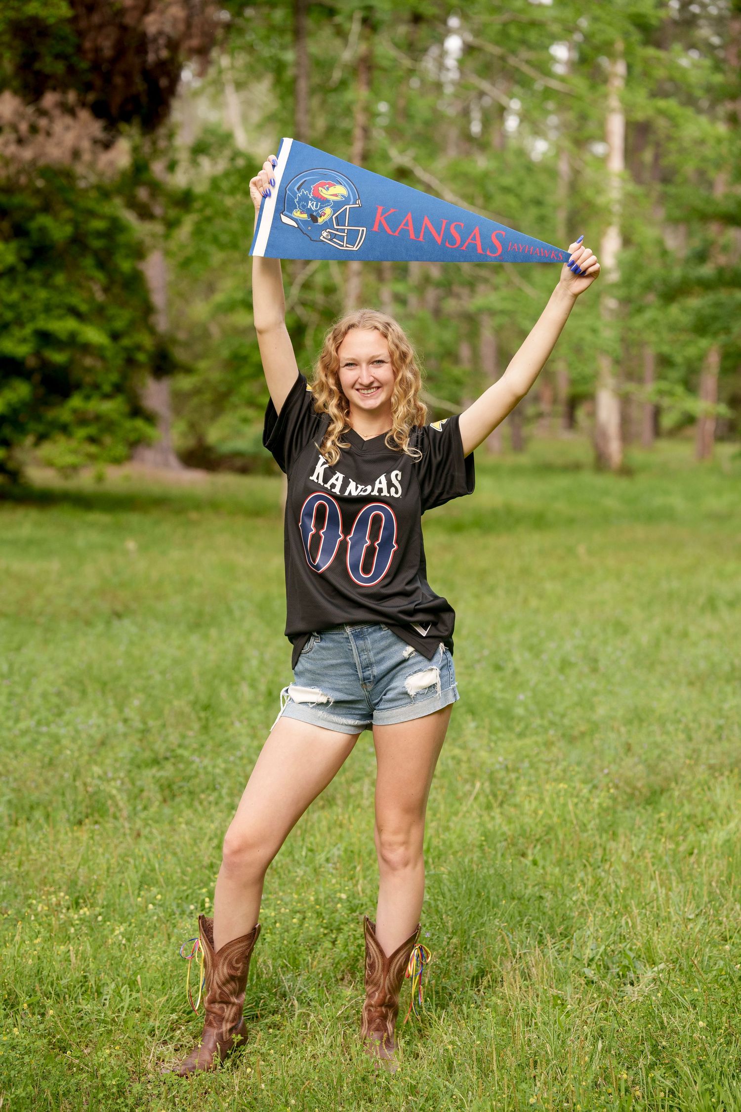 Posing with college gear and boots outdoors for senior photos.  The woodlands senior photographer college session