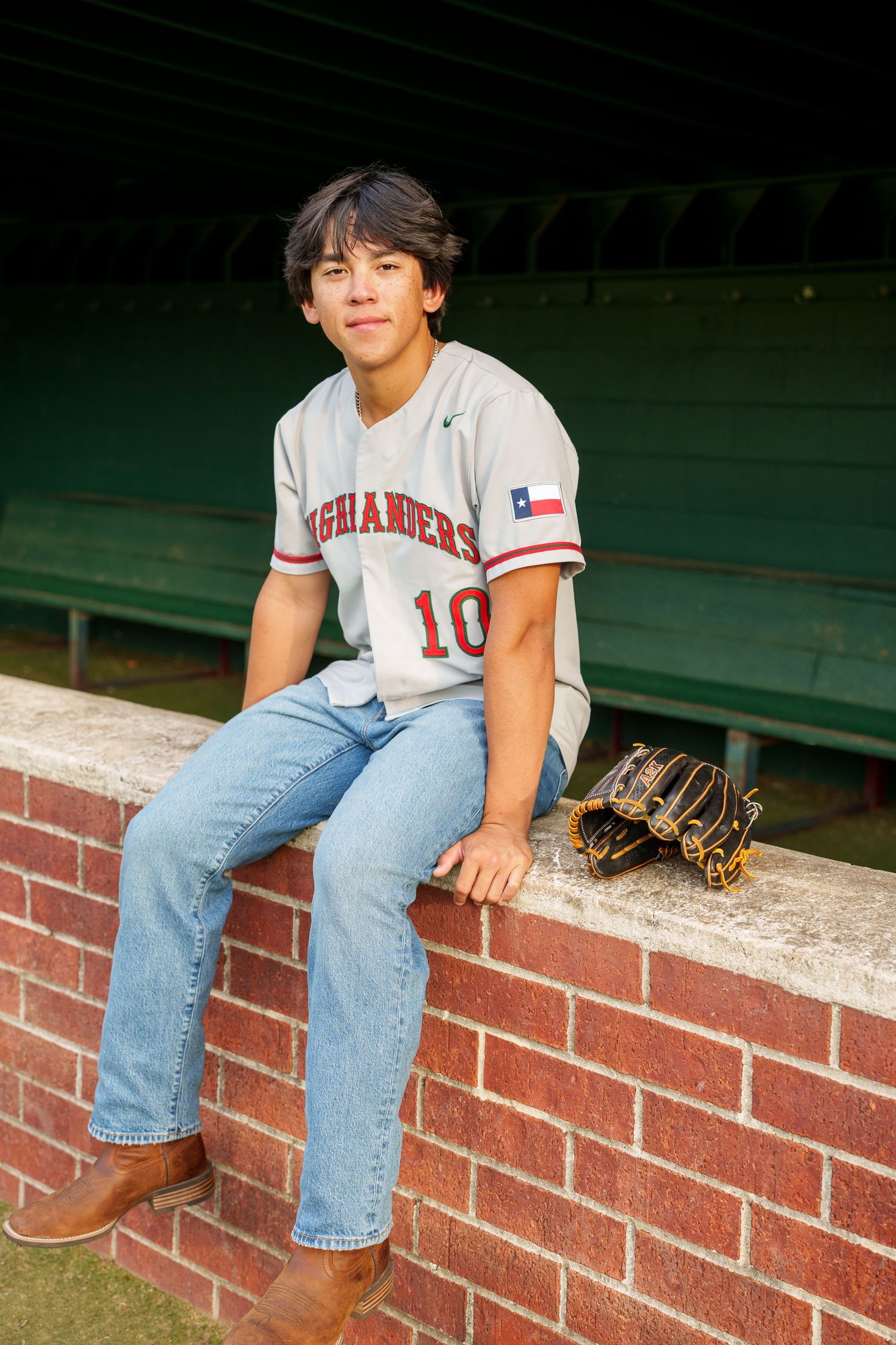 senior baseball player in the woodlands.  dugout senior photos with mitt and jersey