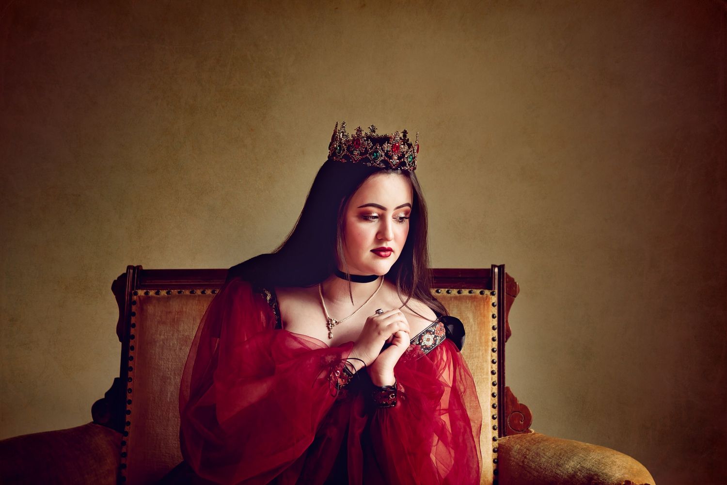 Regal fine art portrait featuring a woman in crimson dress and crown — moody light and timeless presence captured by ja’nicole;art