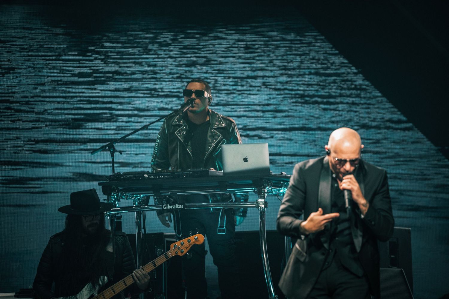 Dramatic concert performance with singer in dark suit silhouetted against blue lighting.