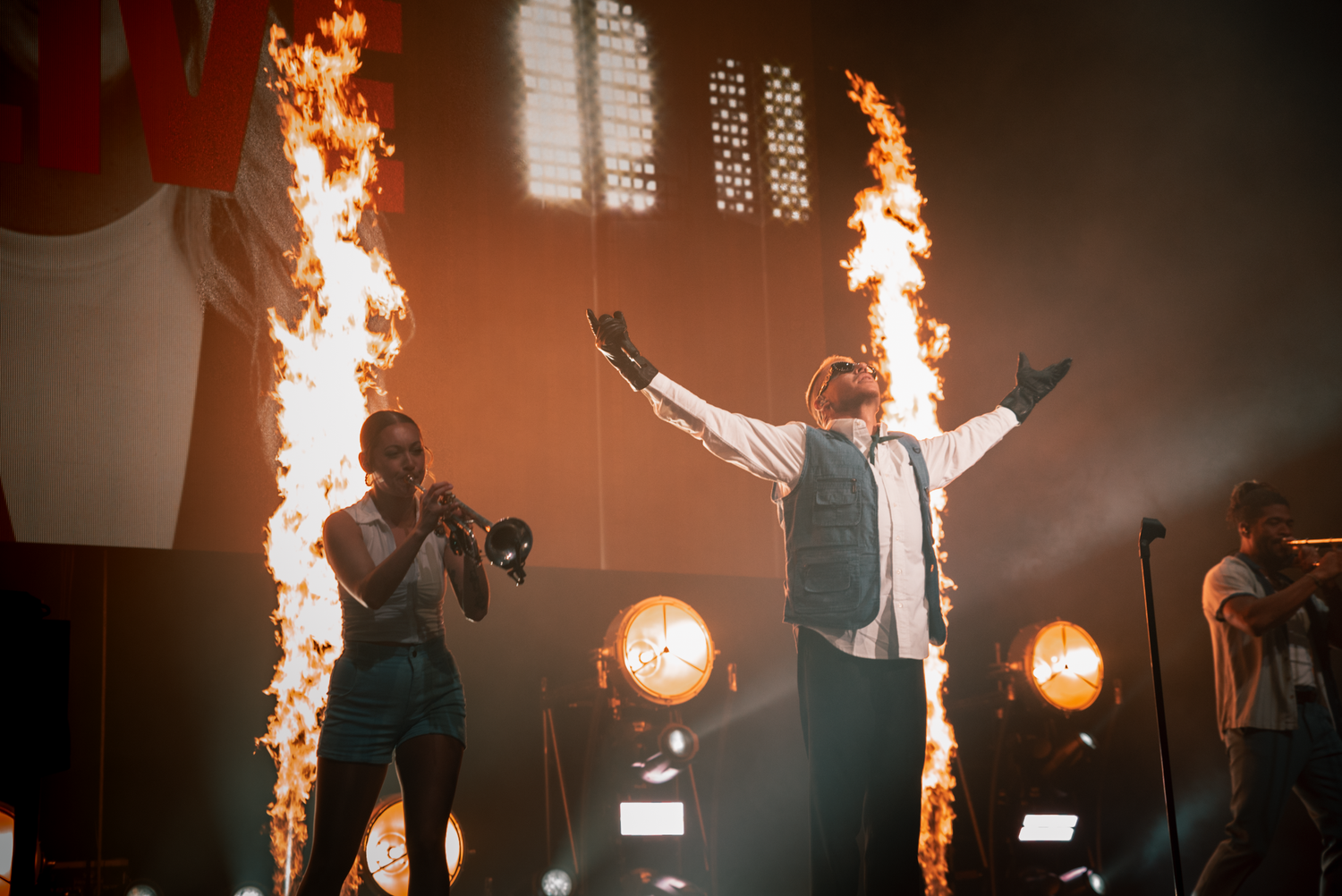 Concert stage lit with fire effects and dramatic orange lighting during performance.