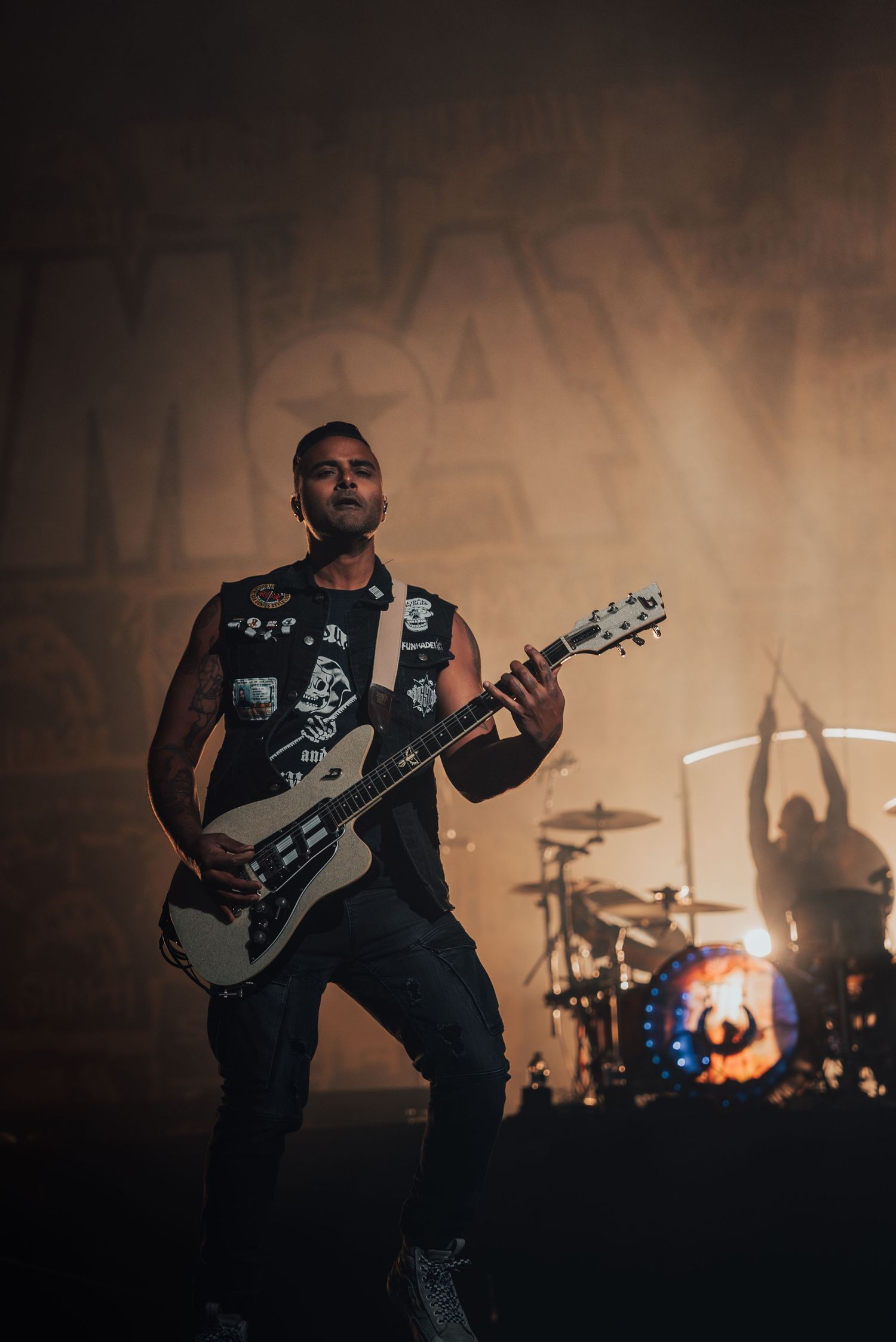Rock musician performs with a guitar on a smoky concert stage with dramatic lighting.