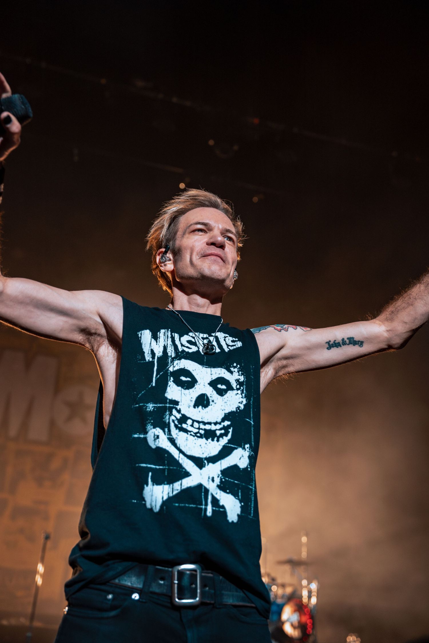 Performer wearing a Misfits t-shirt with iconic skull design performing on a dark stage.