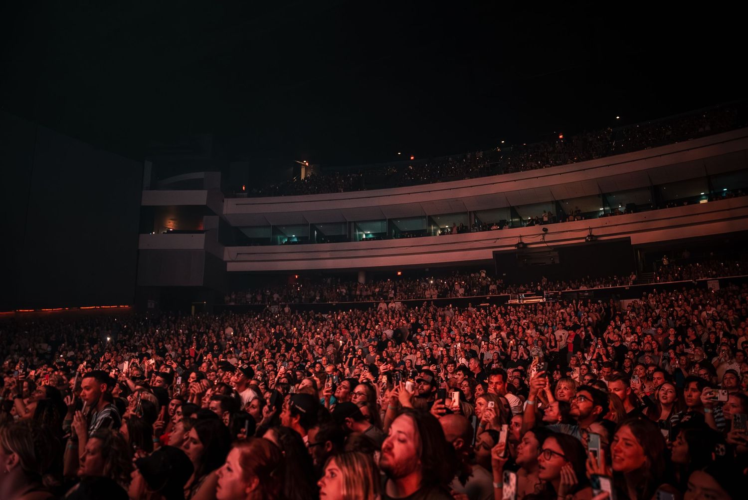 Panoramic view of a packed concert arena with thousands of fans in attendance.