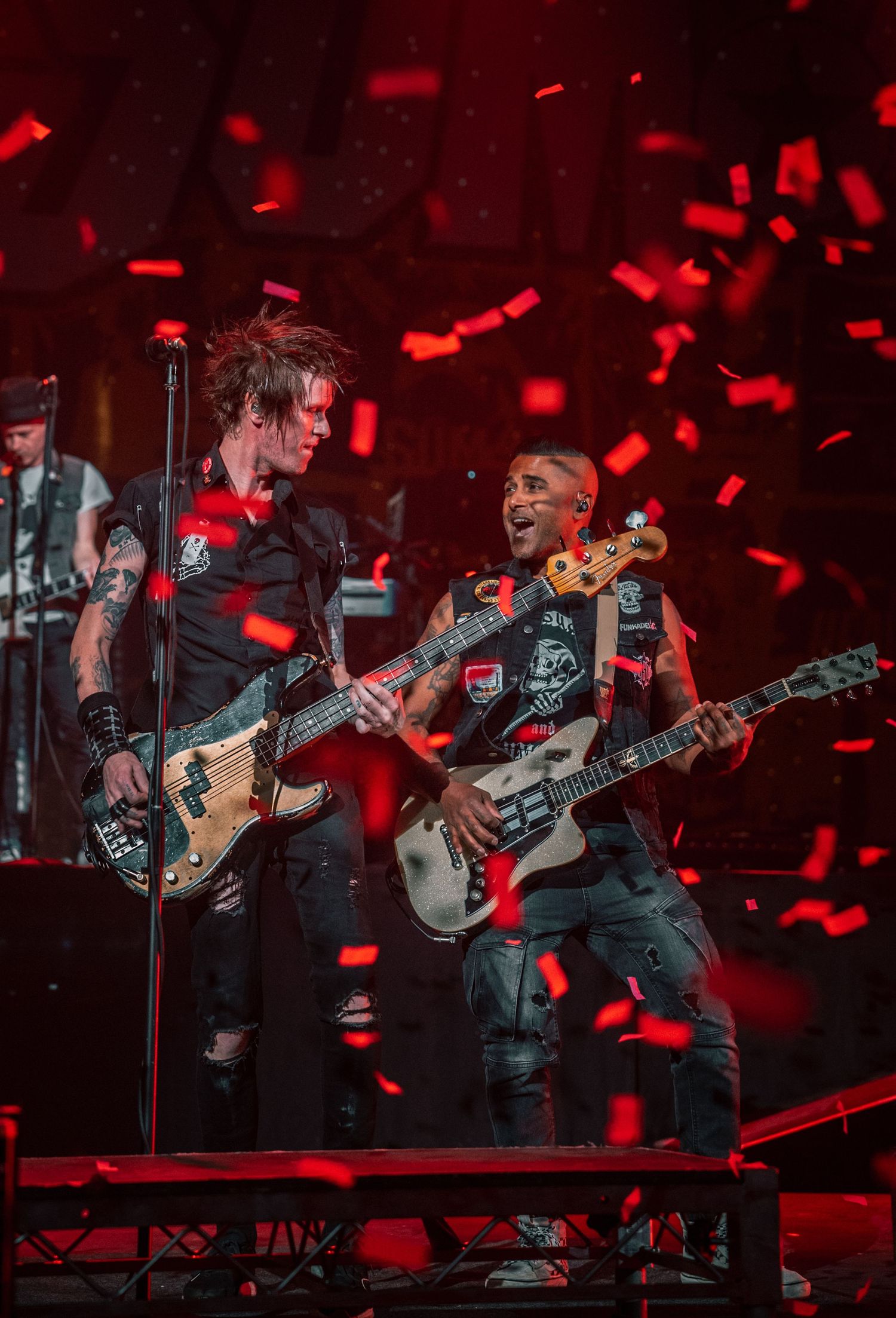 Rock band performs under red lighting with dramatic stage effects.