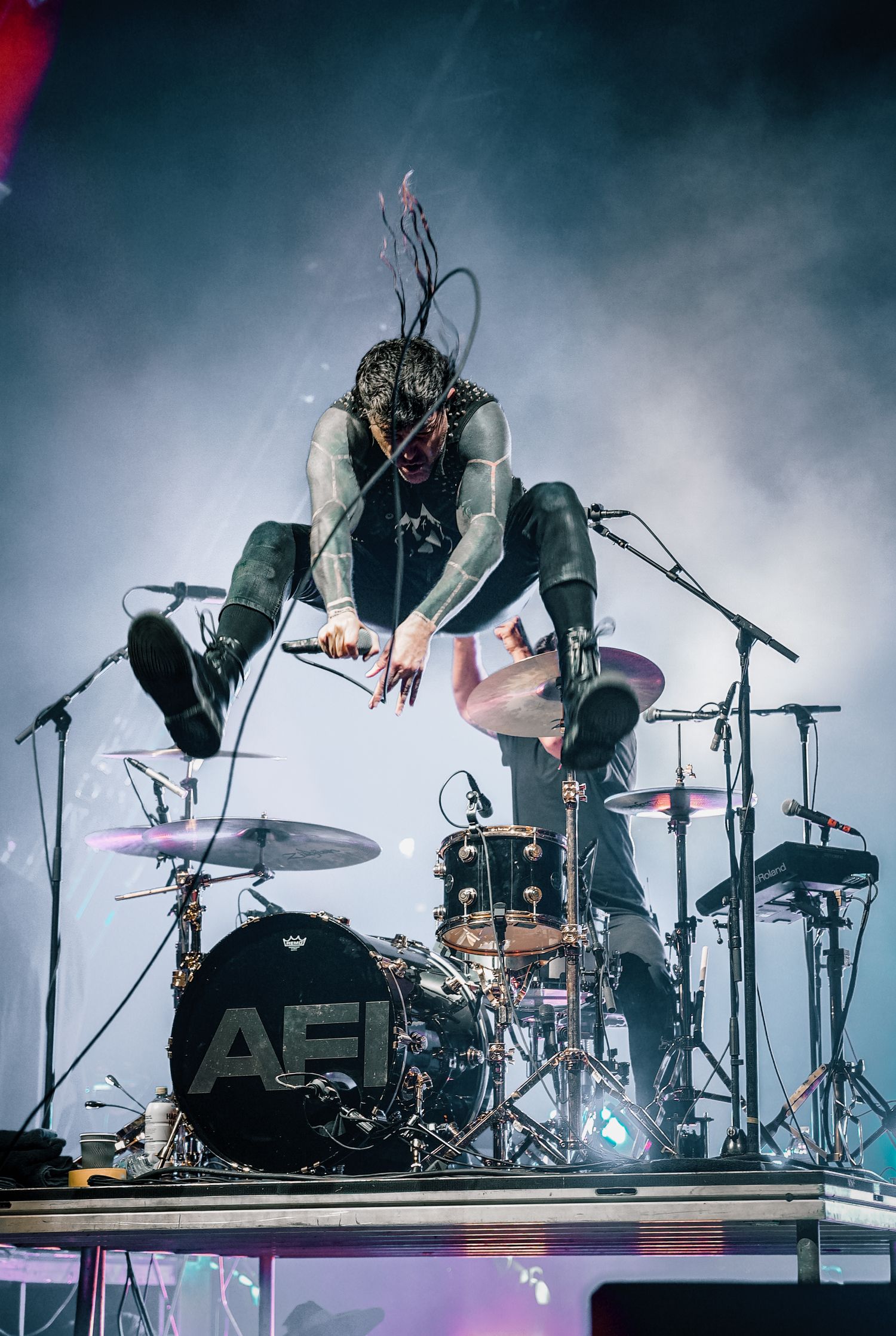 Atmospheric concert shot showing musicians performing with fog and dramatic lighting effects.