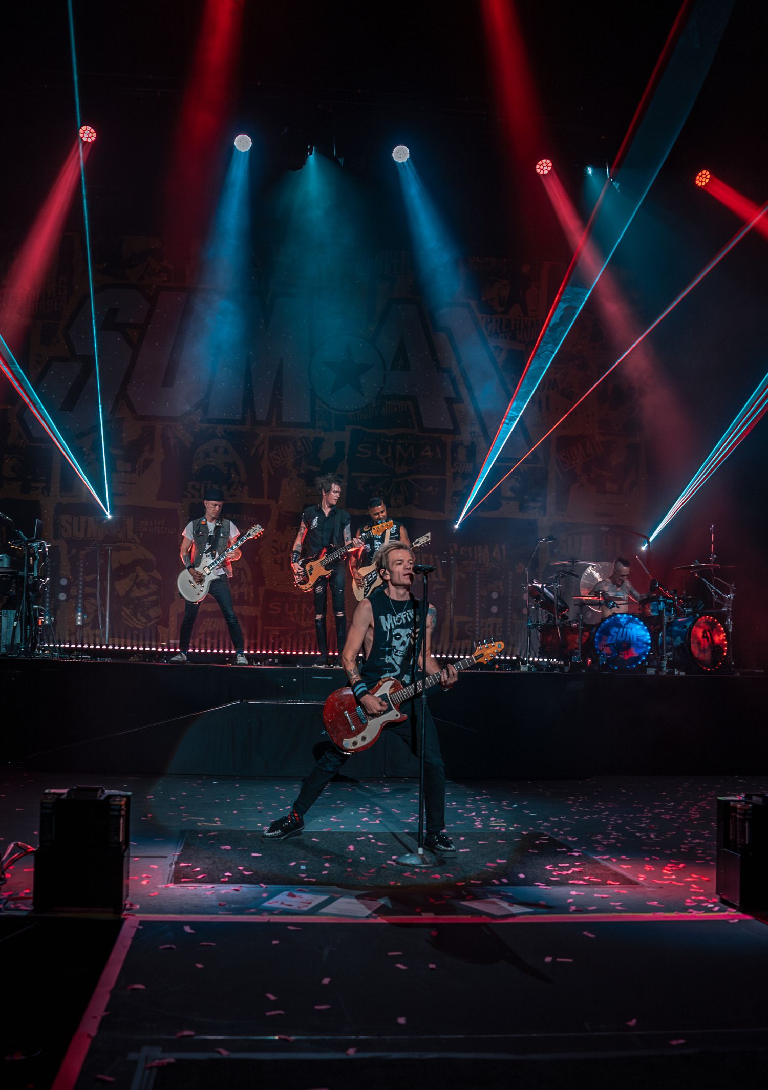 Wide shot of rock band performing with dramatic blue and red lighting effects.