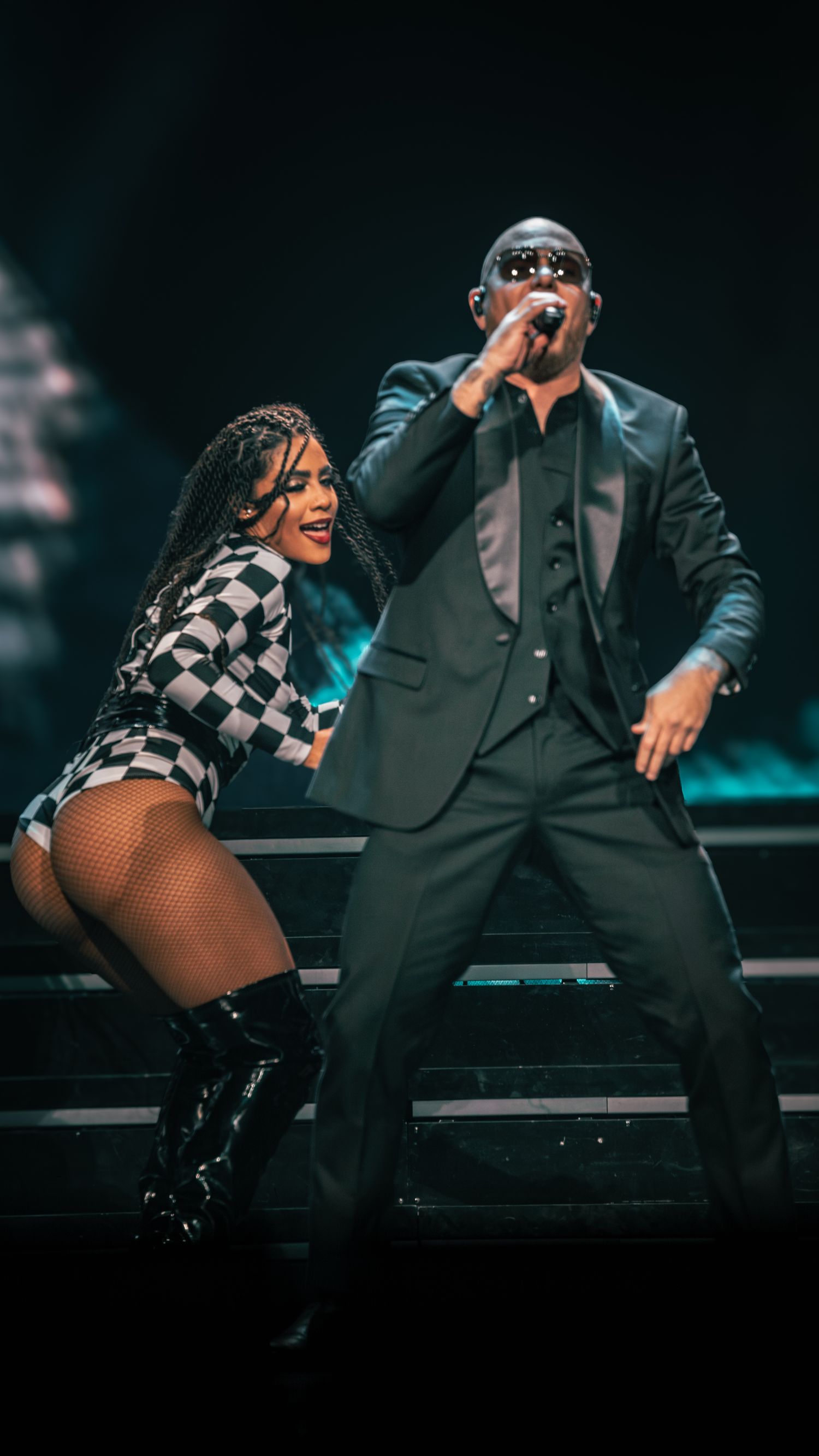 Energetic performance on stage with dancer in checkered outfit and performer in dark suit.