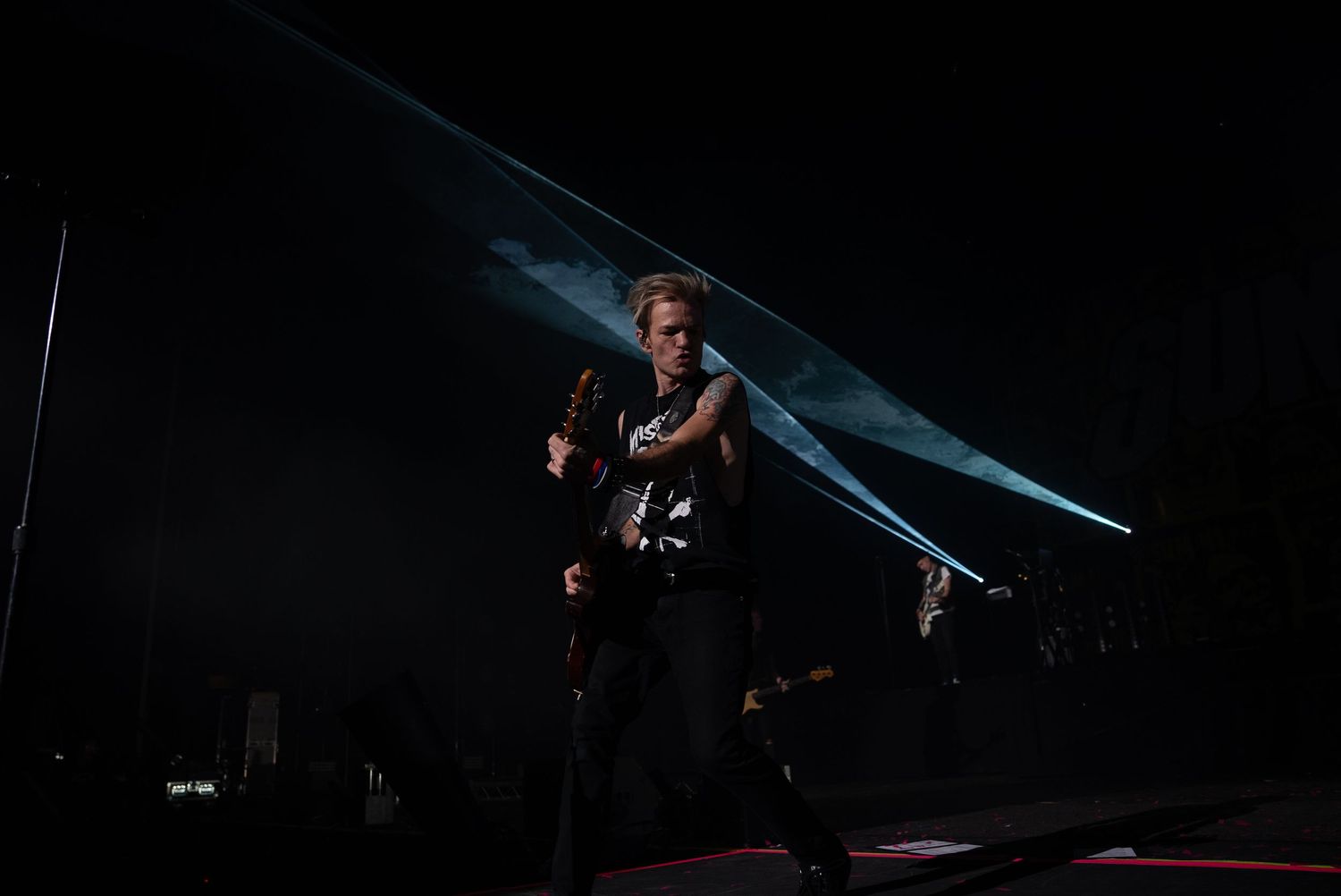 Rock musician performing passionately on darkened stage with dramatic lighting.