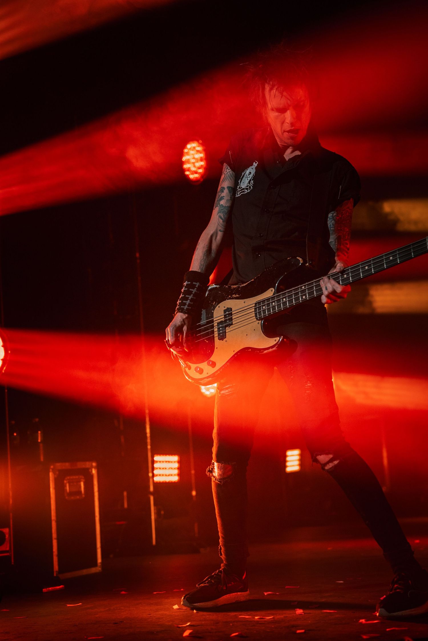 Bass player performs under intense red stage lighting during concert.