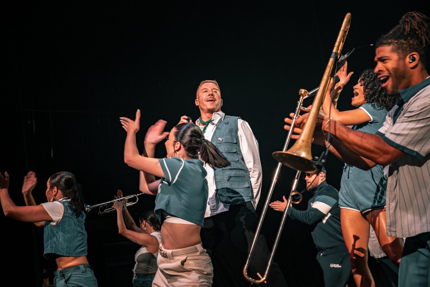 Musicians playing brass instruments on stage during an energetic performance.
