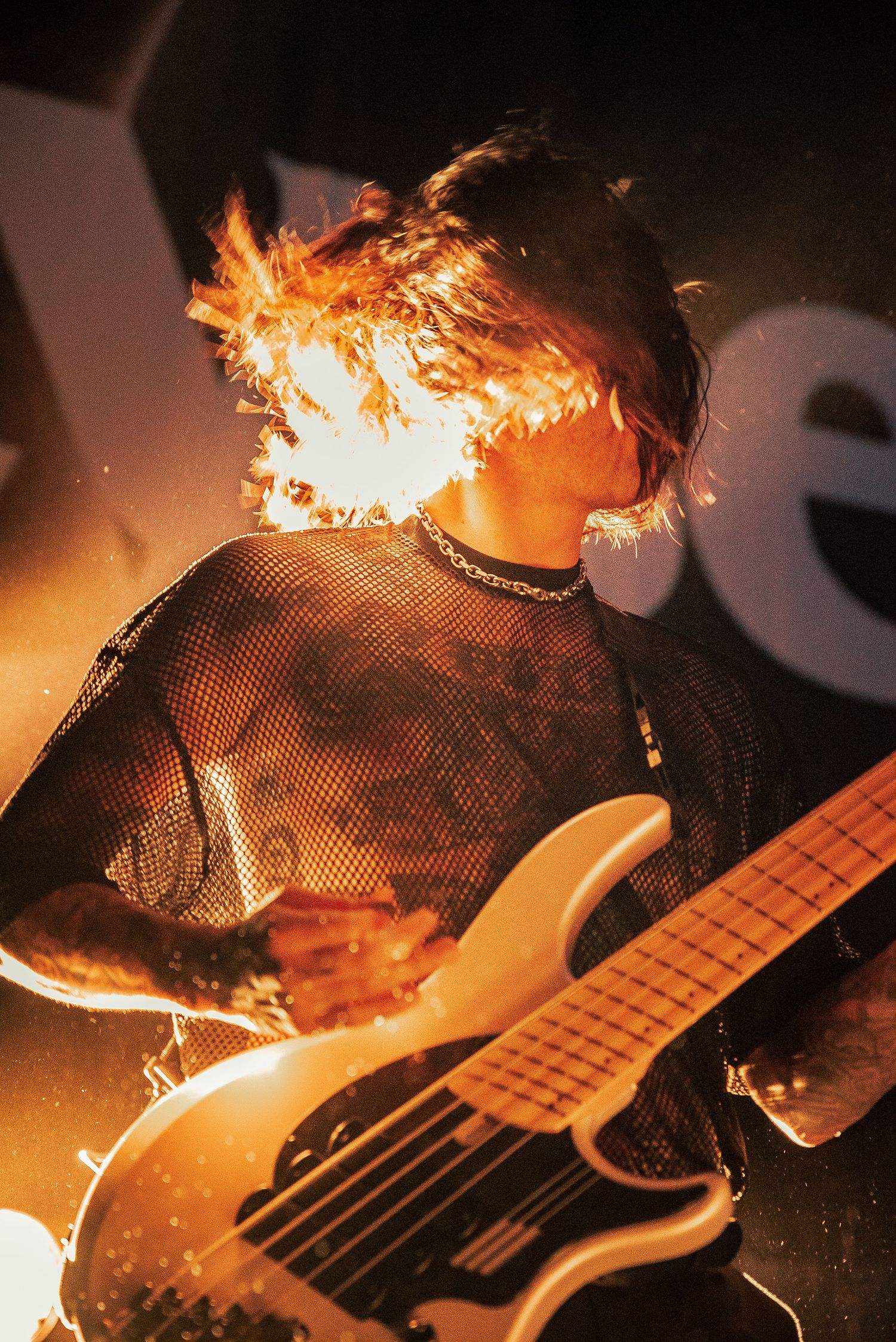 Bassist plays instrument during dramatic performance with intense fire lighting effects.