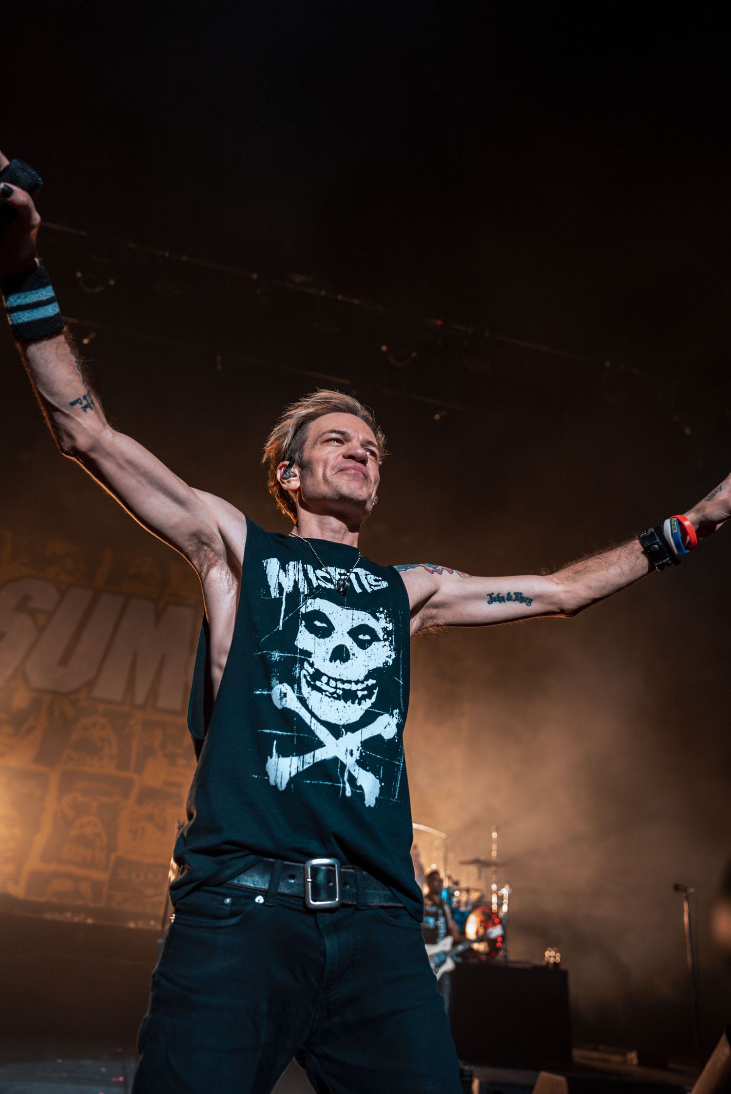 Rock musician in a Misfits t-shirt performs energetically on stage with dramatic lighting.