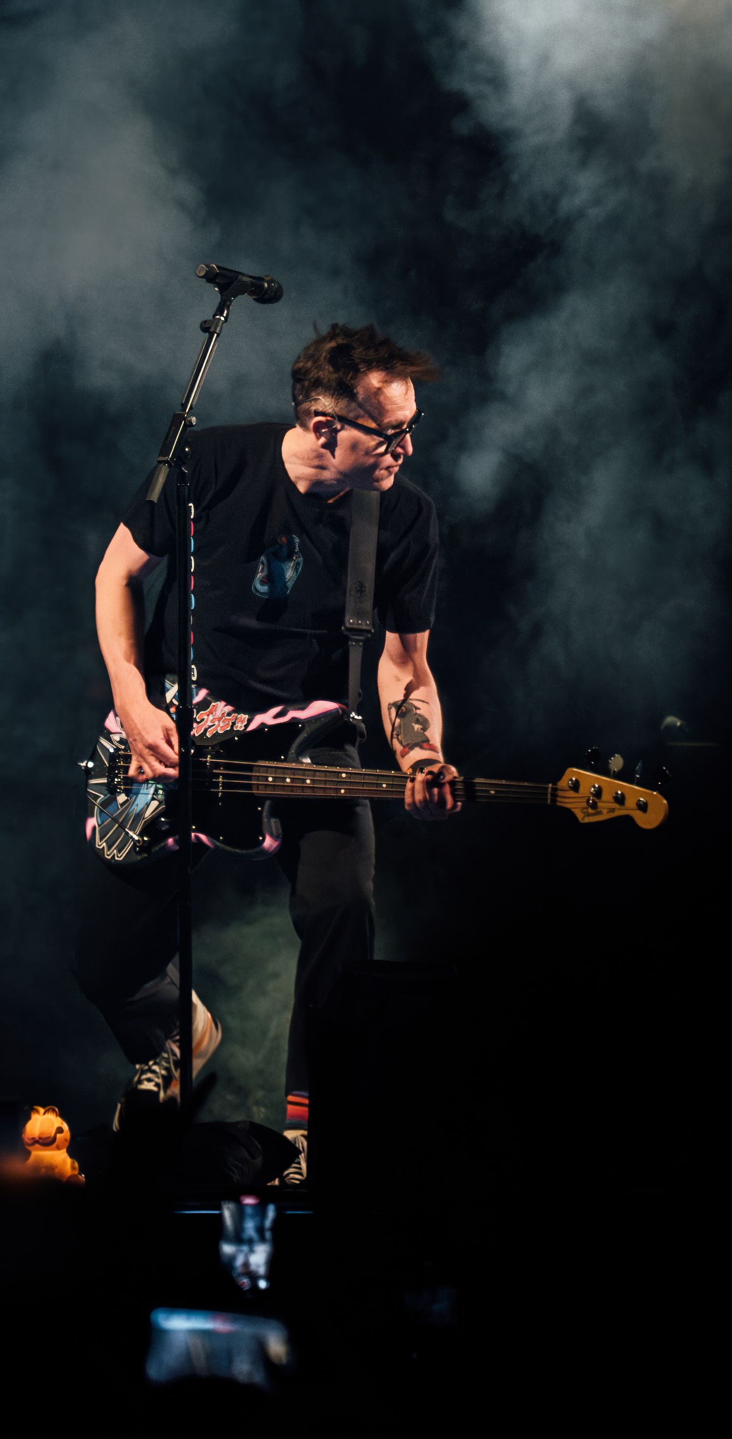 Bassist plays guitar in dramatic stage lighting during live performance.