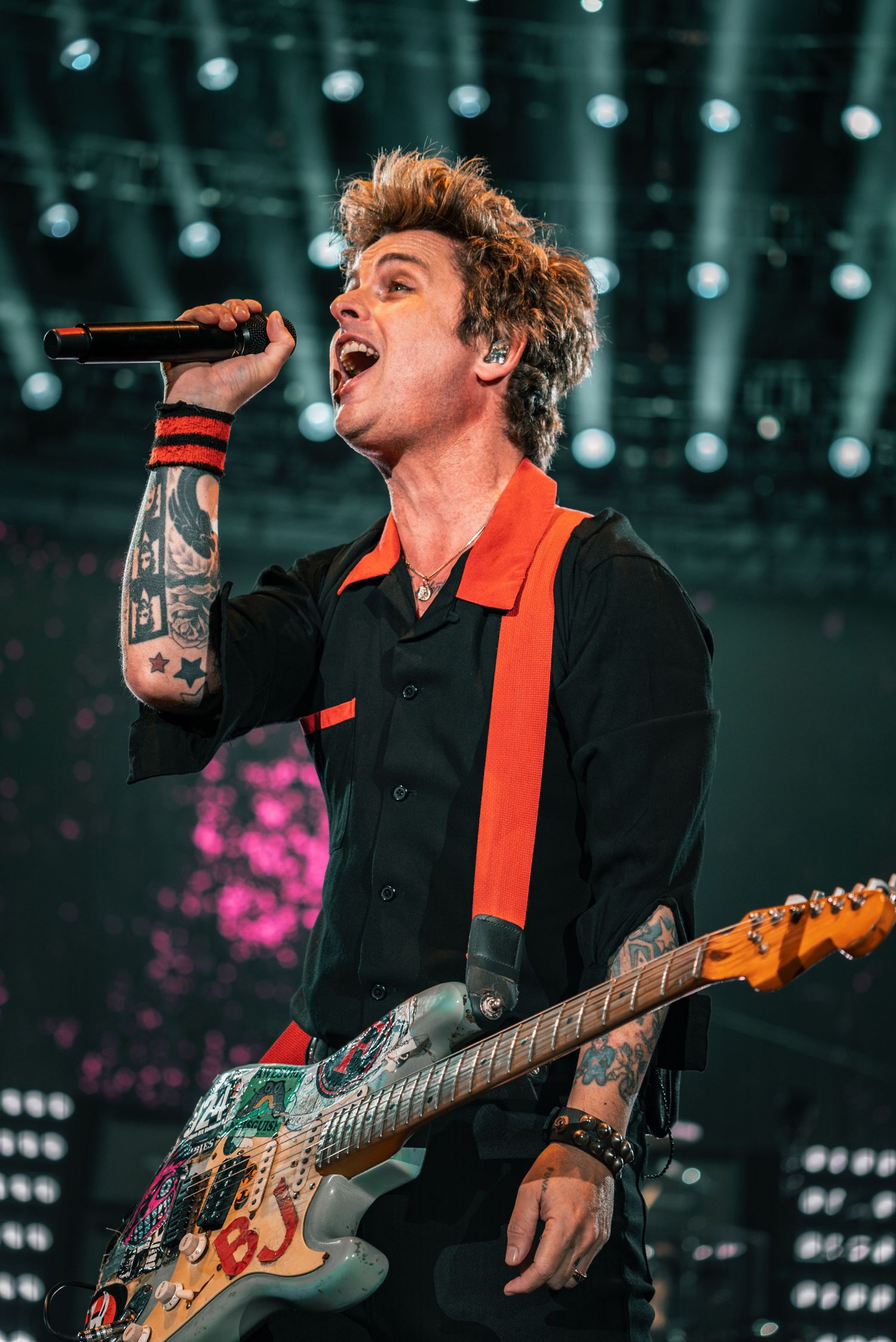 A passionate musical performance captured mid-song with teal lighting and stage effects in the background.