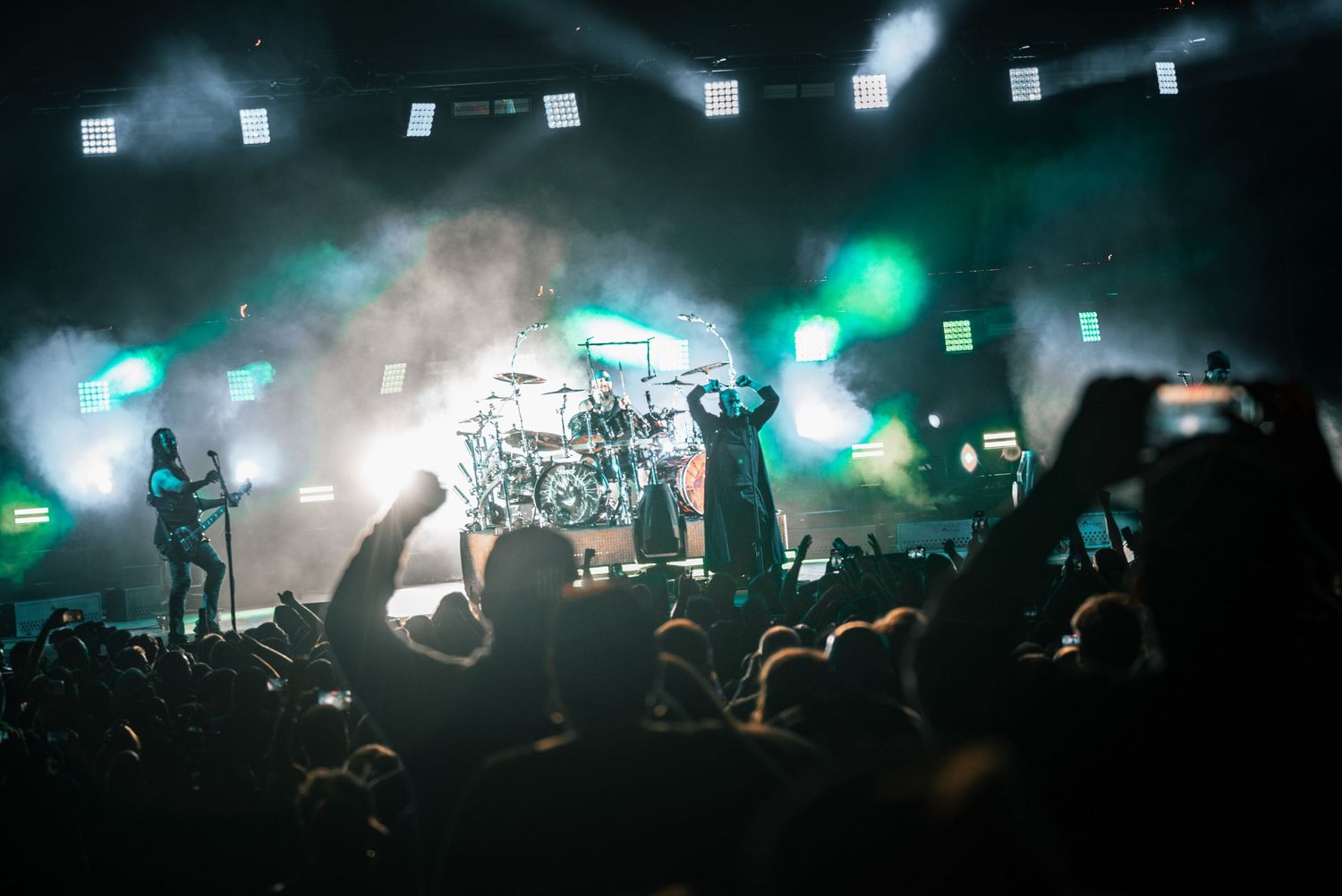 Concert venue lit with atmospheric blue and green lighting effects above crowd silhouettes.