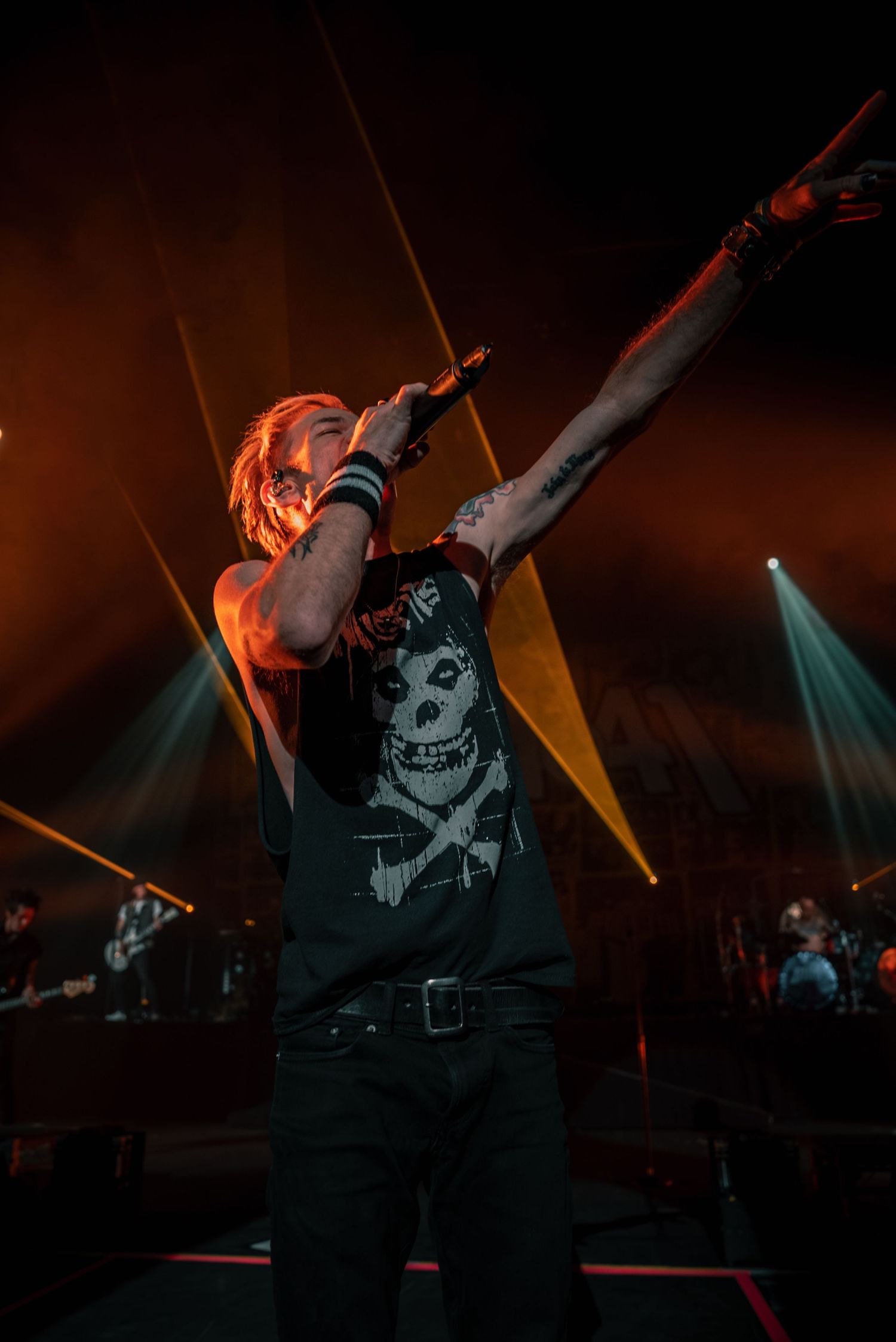 Rock artist performs energetically under dramatic orange stage lighting.