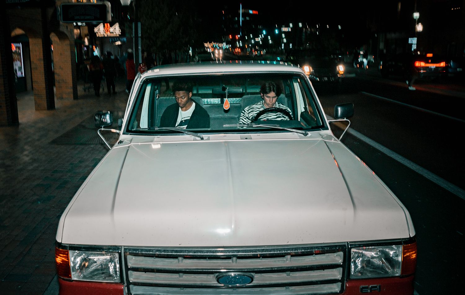 Front view of classic white car with occupants visible through windshield at night.