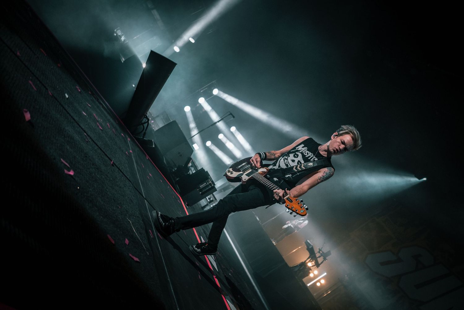Stage performance captured with dramatic white spotlight beams cutting through darkness.