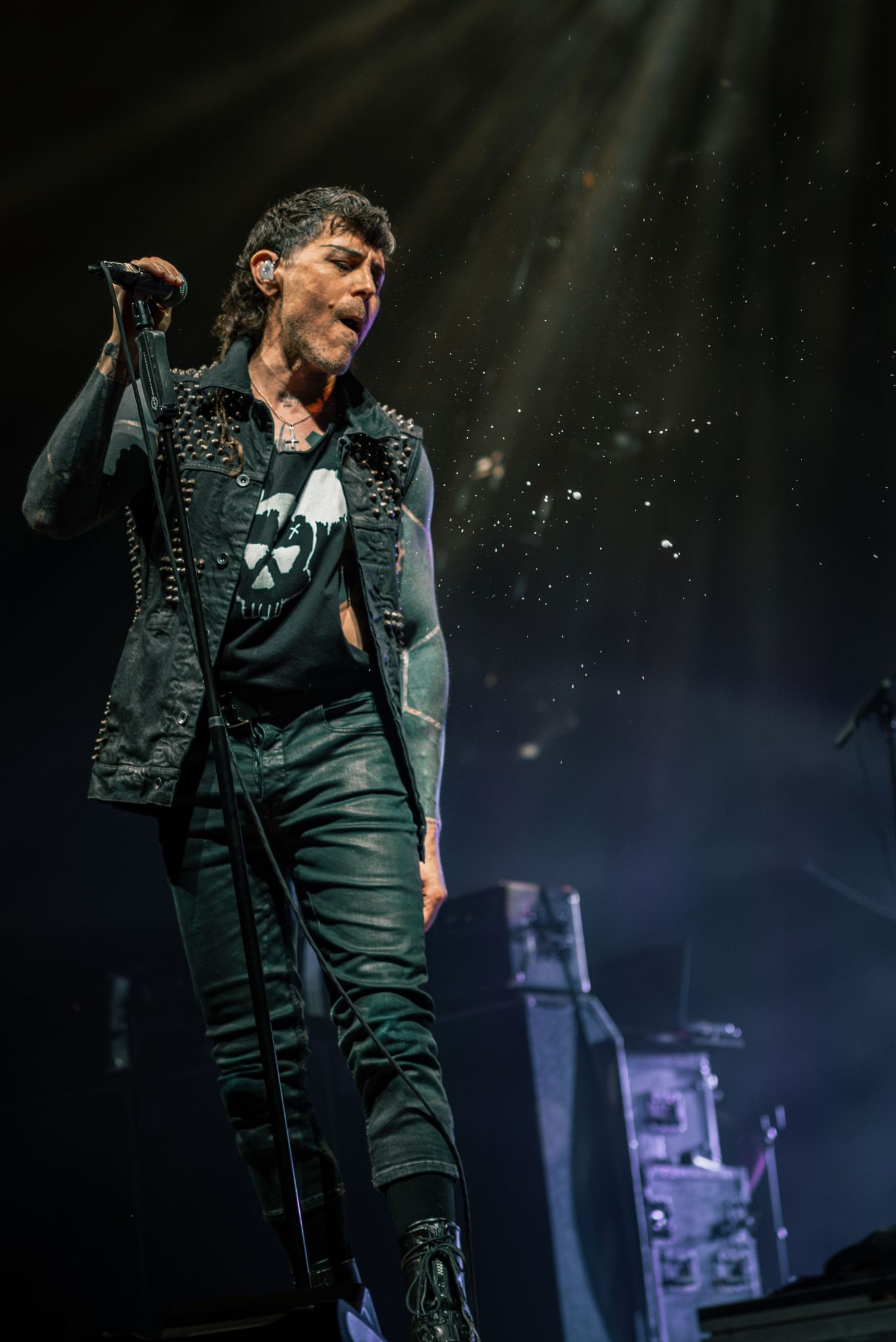 Stage performer in dark outfit photographed during dramatic concert lighting.
