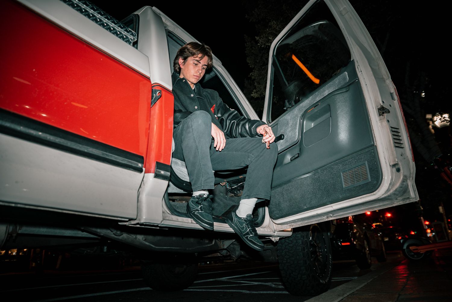 Side view of someone sitting in truck doorway at night with dramatic lighting.