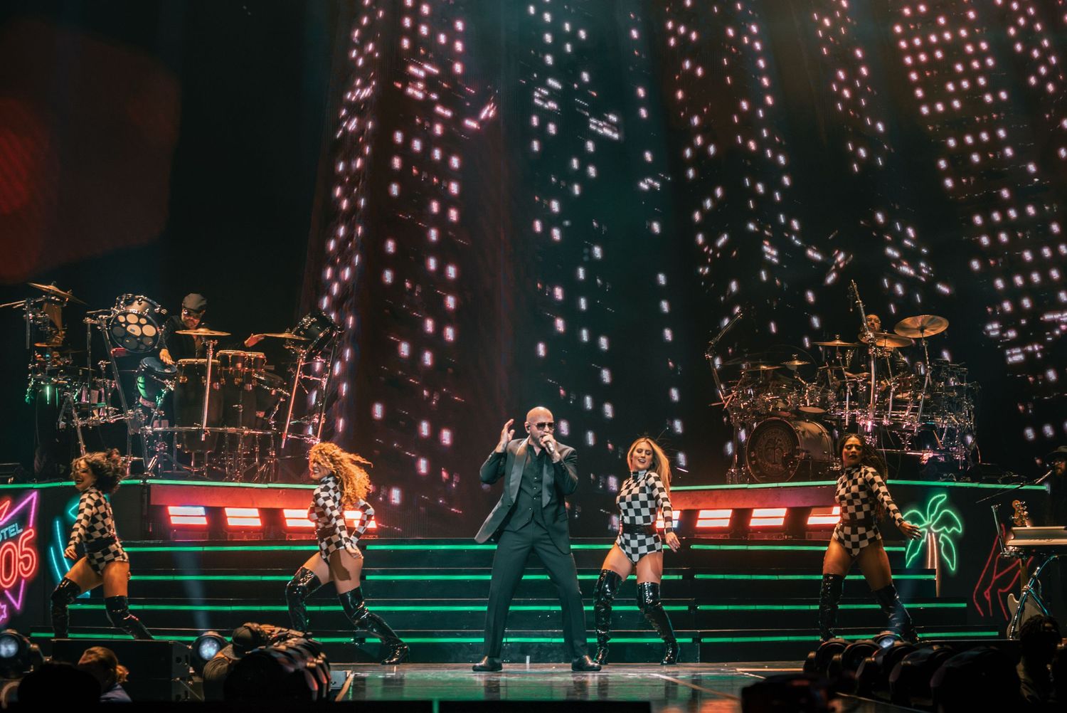 Wide shot of concert stage with bright twinkle light backdrop and green accents.