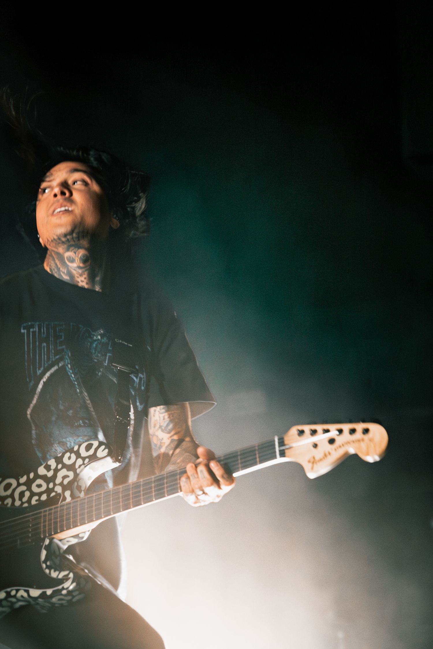 Guitarist performs under atmospheric green lighting with electric guitar during intense concert moment.