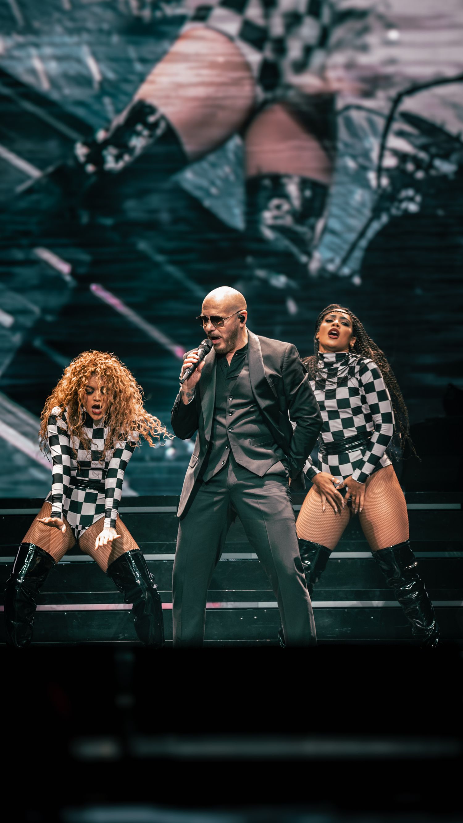 High-energy dance performance with multiple performers in coordinated black and checkered outfits.