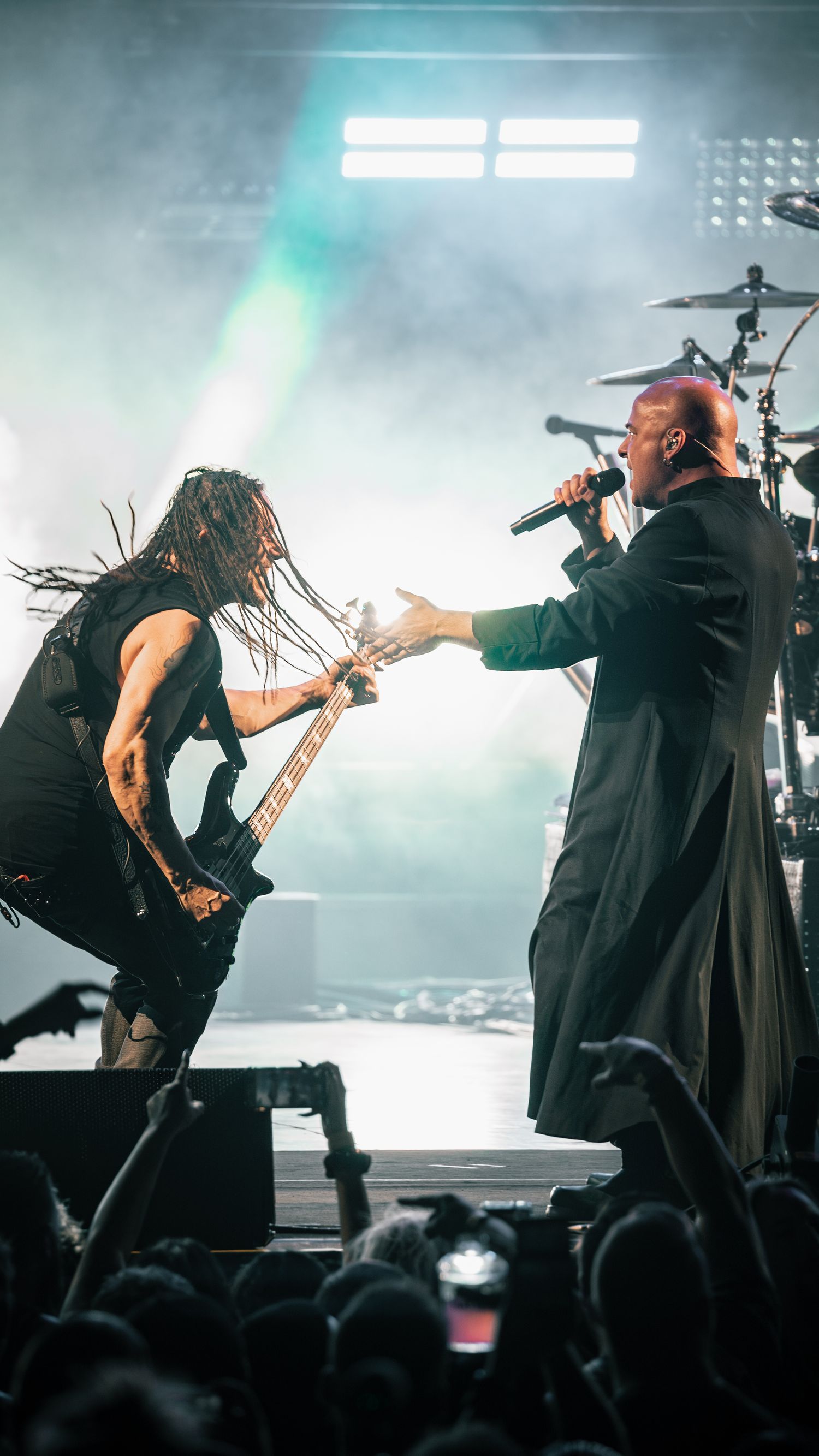 Energetic stage performance with musicians in black attire under bright stage lighting.