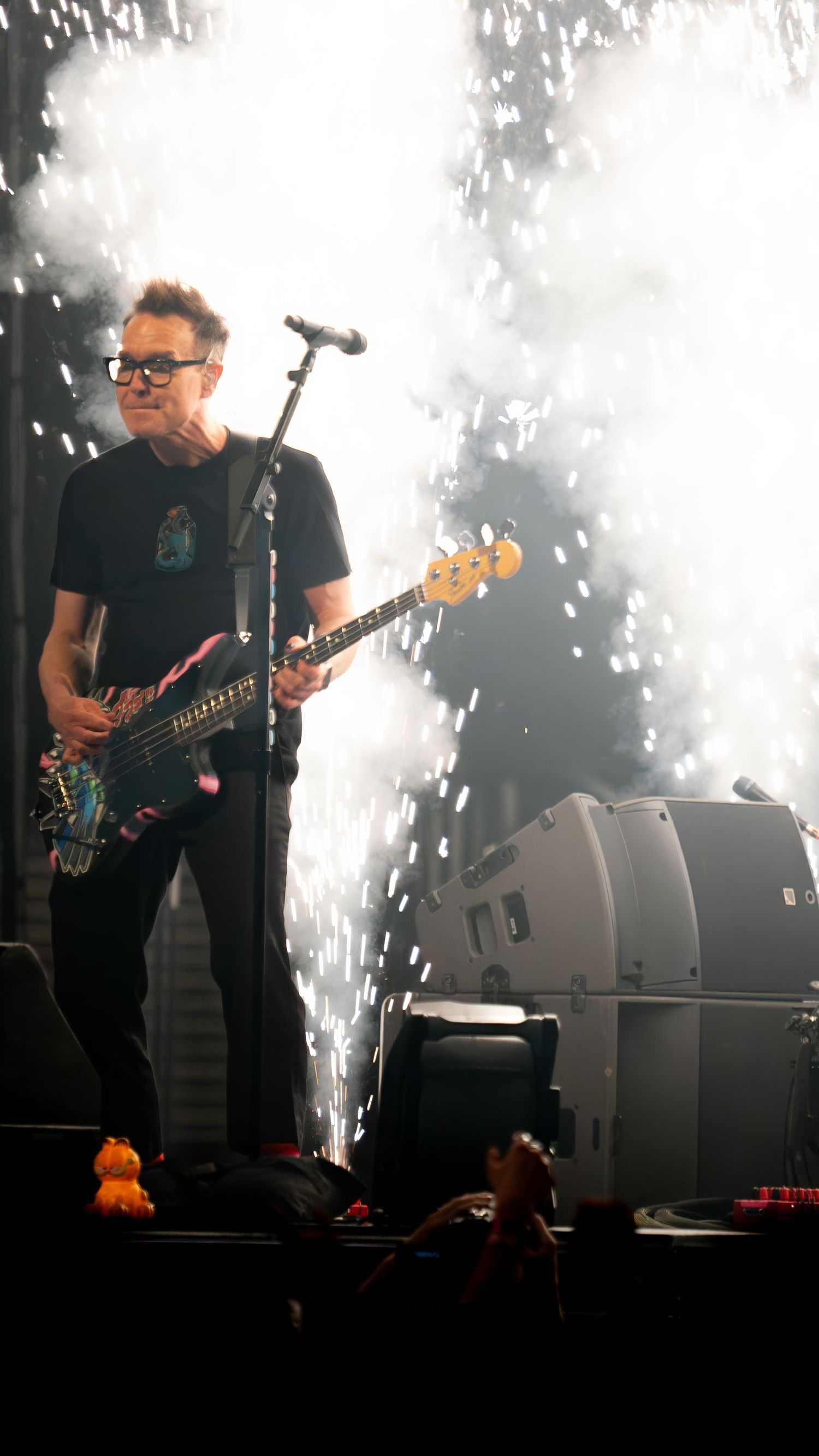 Musicians perform with bright pyrotechnic effects and white sparks illuminating the stage.