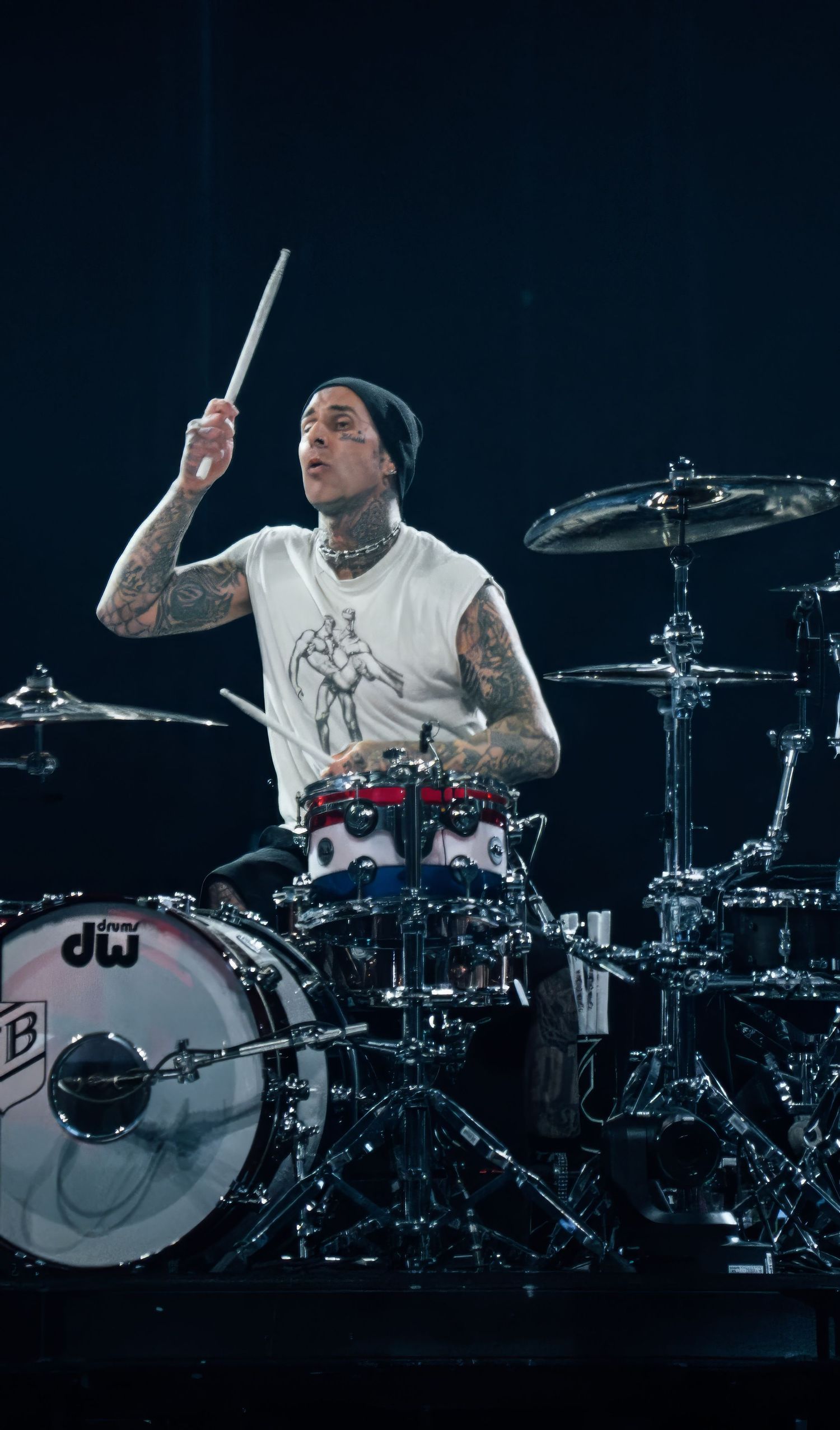 Professional drummer performing on illuminated stage with multiple drums and cymbals.
