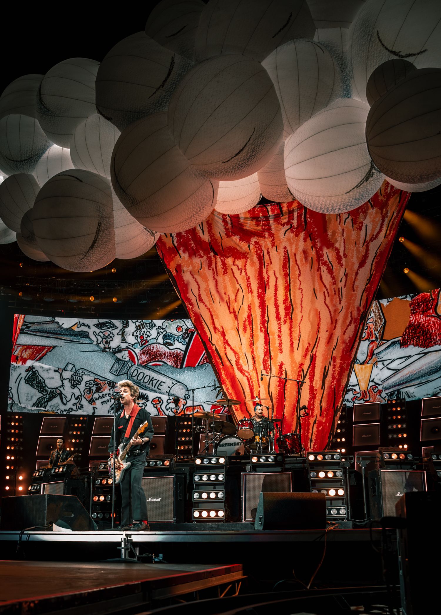 Concert venue with dramatic cloud-like ceiling installations and orange ambient lighting.