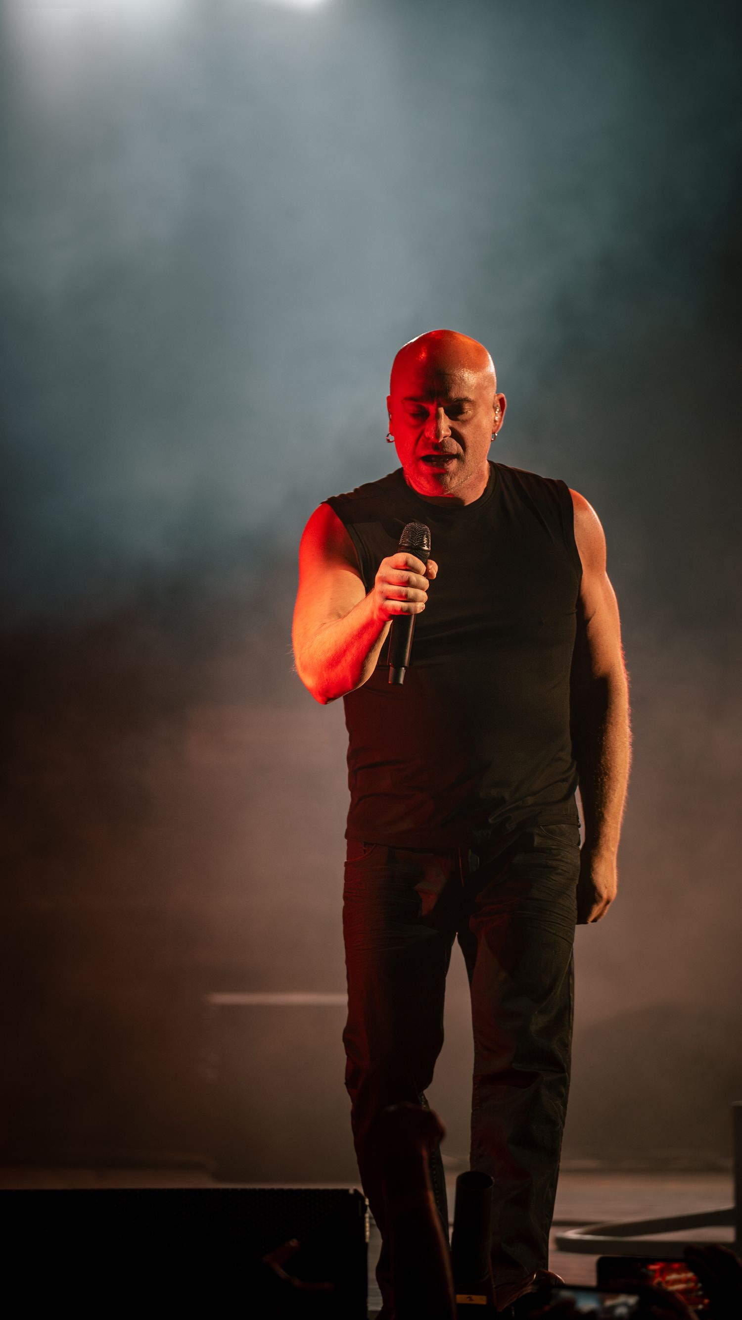 Dramatic stage performance captured in moody lighting with smoke effects.