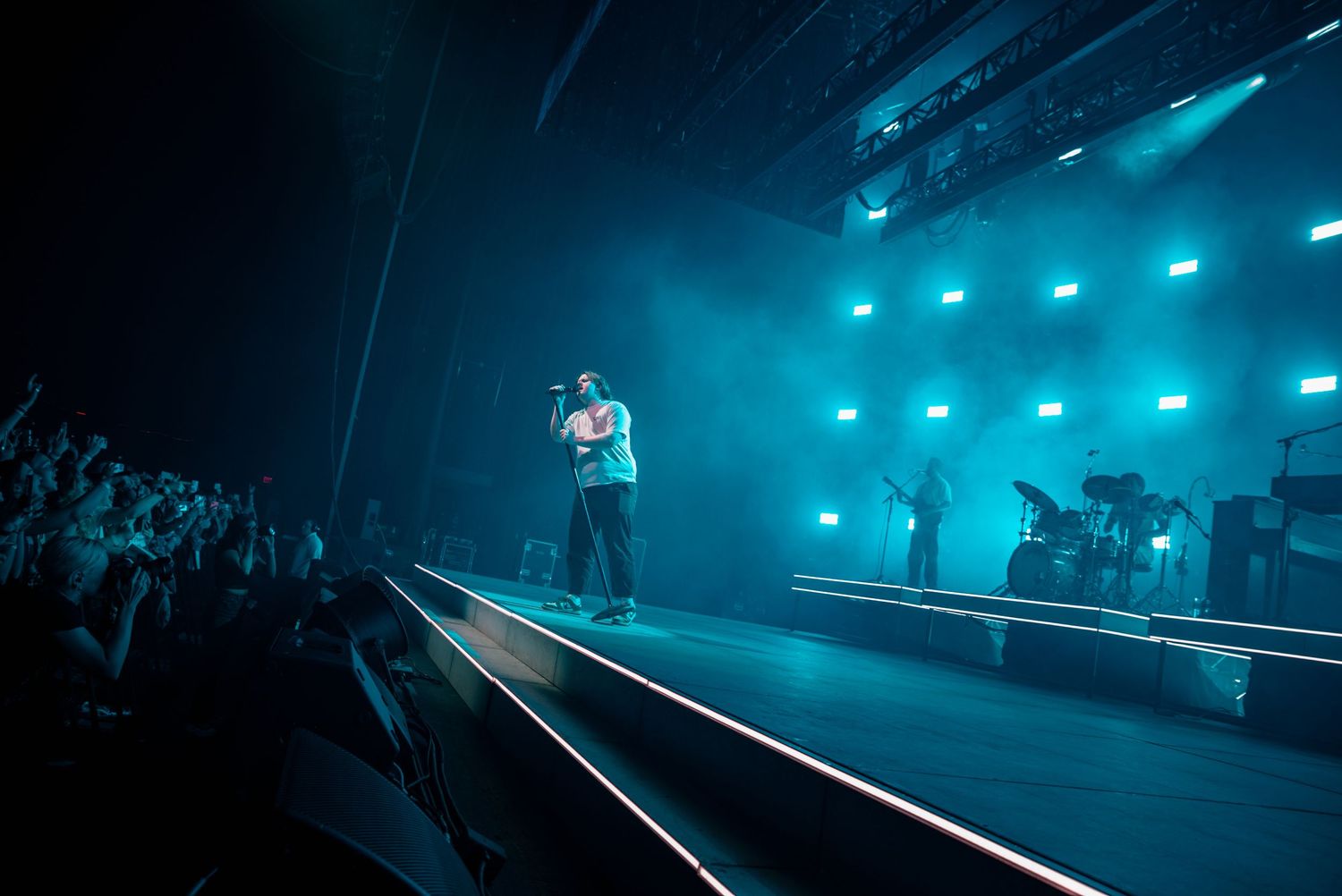 Concert stage setup illuminated by teal-colored lighting creating a dramatic atmosphere.