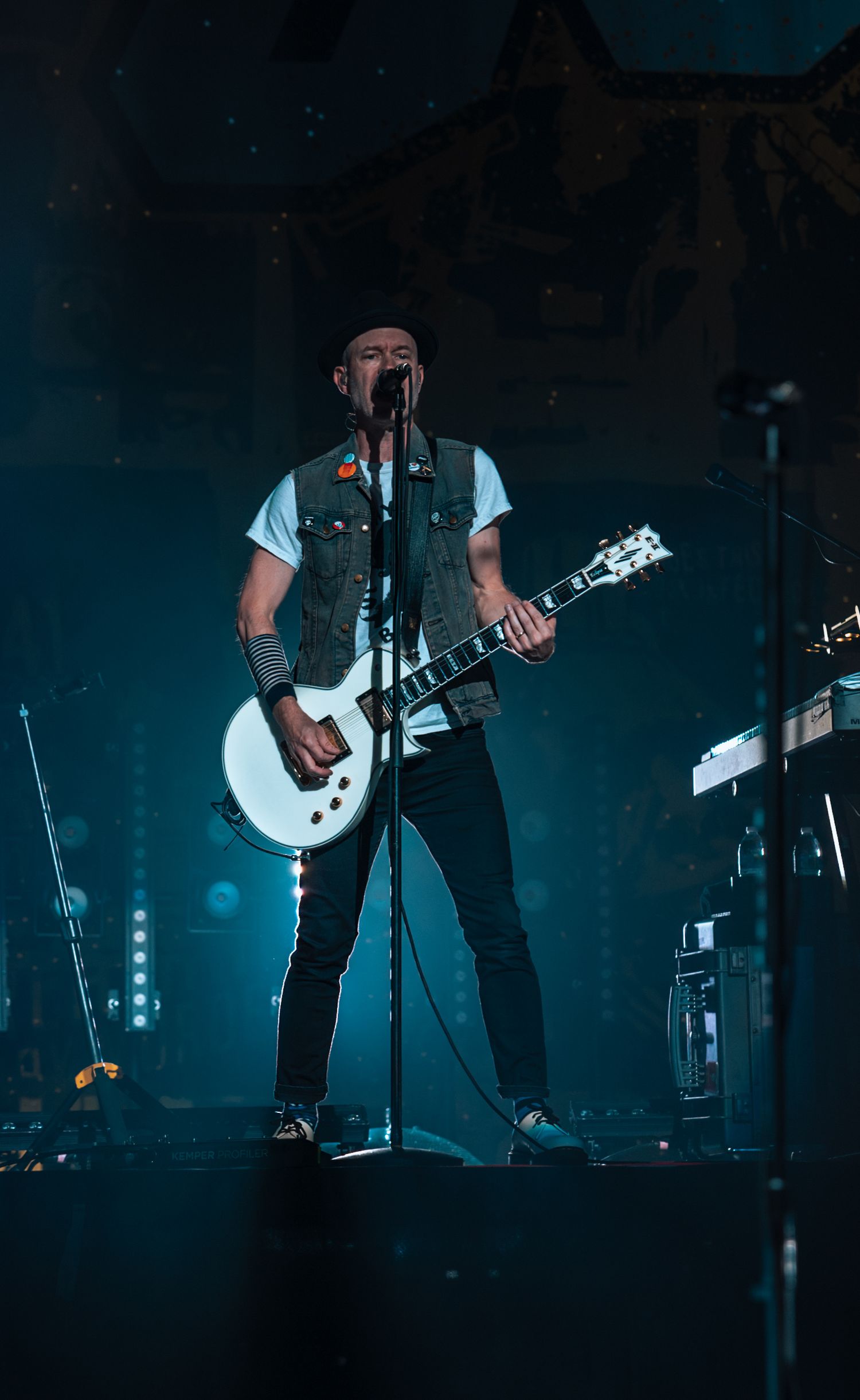 Bass player performs in dramatic blue stage lighting during rock concert.