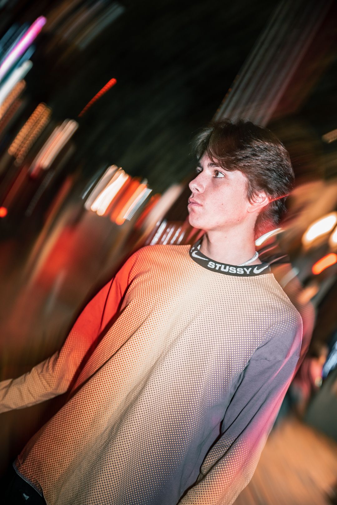 Profile shot in motion blur with urban nighttime lighting creating atmospheric effect.