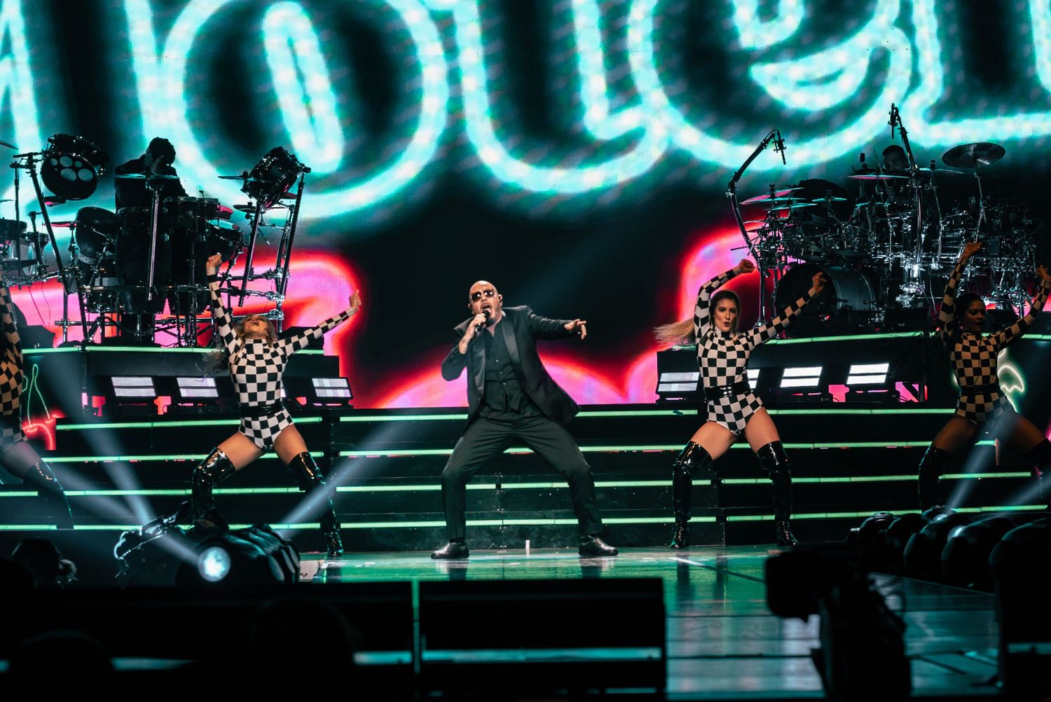 Stage performance with bright blue neon lighting and performers on multiple levels.