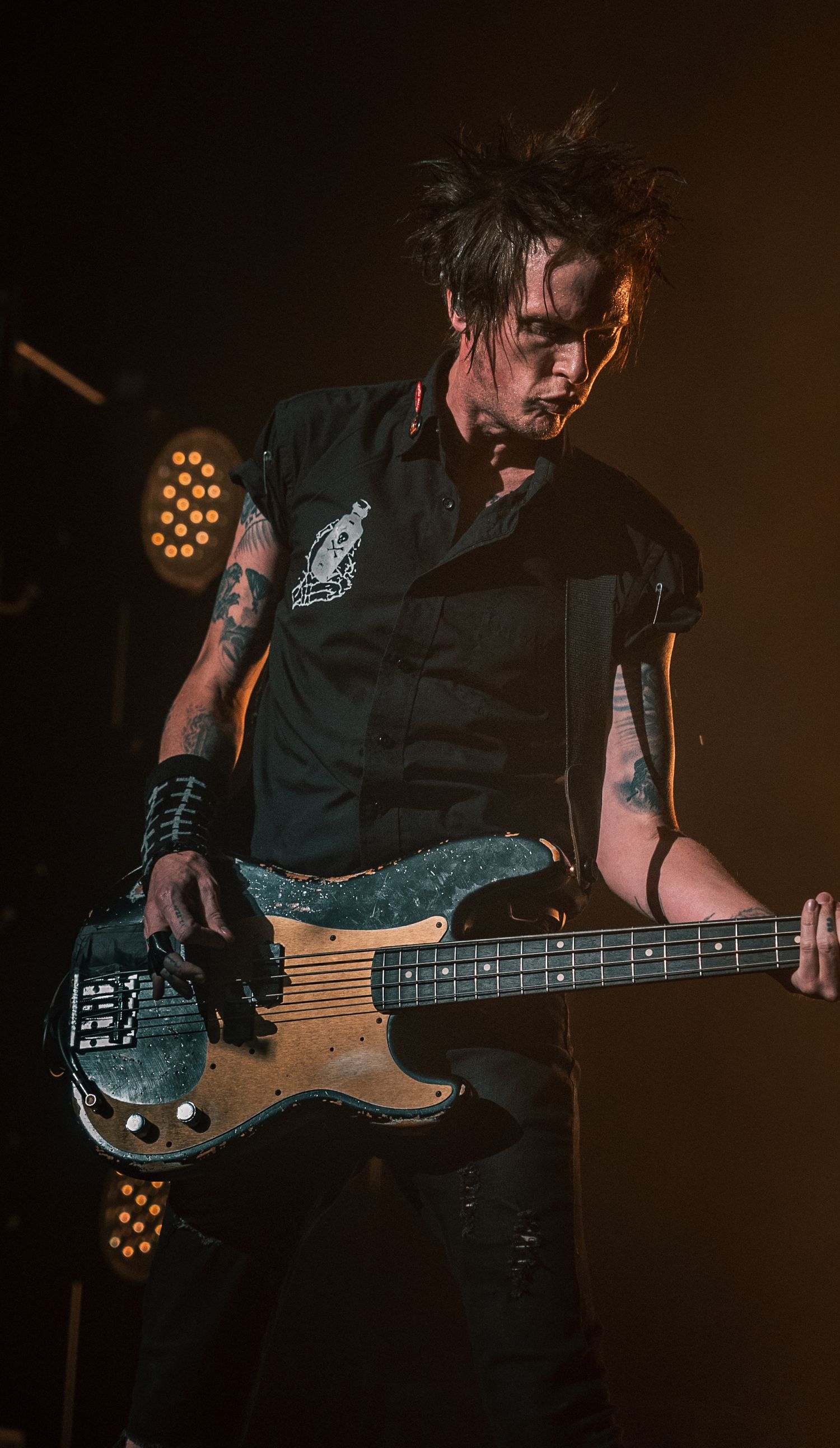 Close-up of bassist playing worn wooden bass guitar during performance.