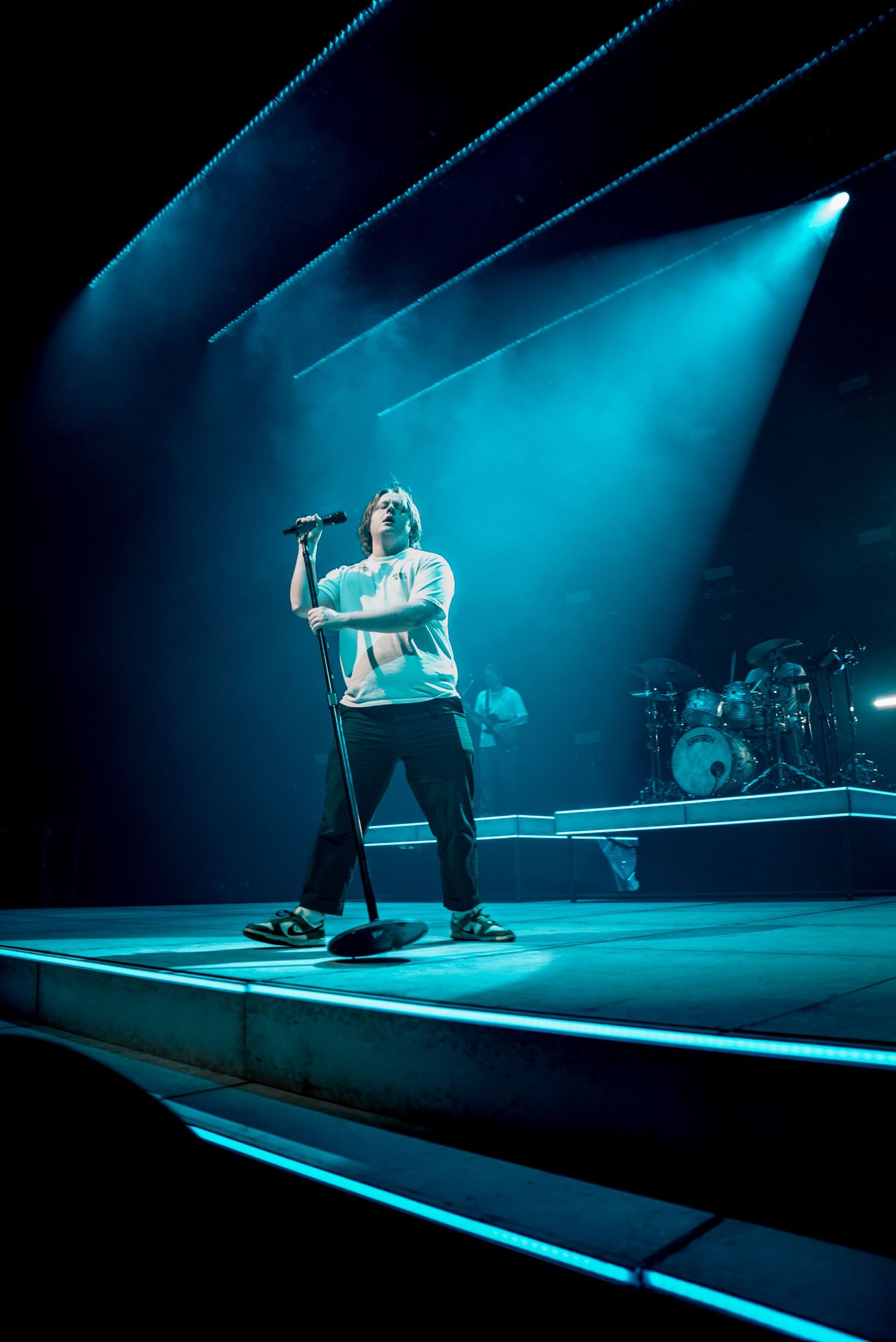Concert stage bathed in dramatic blue lighting with performer silhouetted against the backdrop.